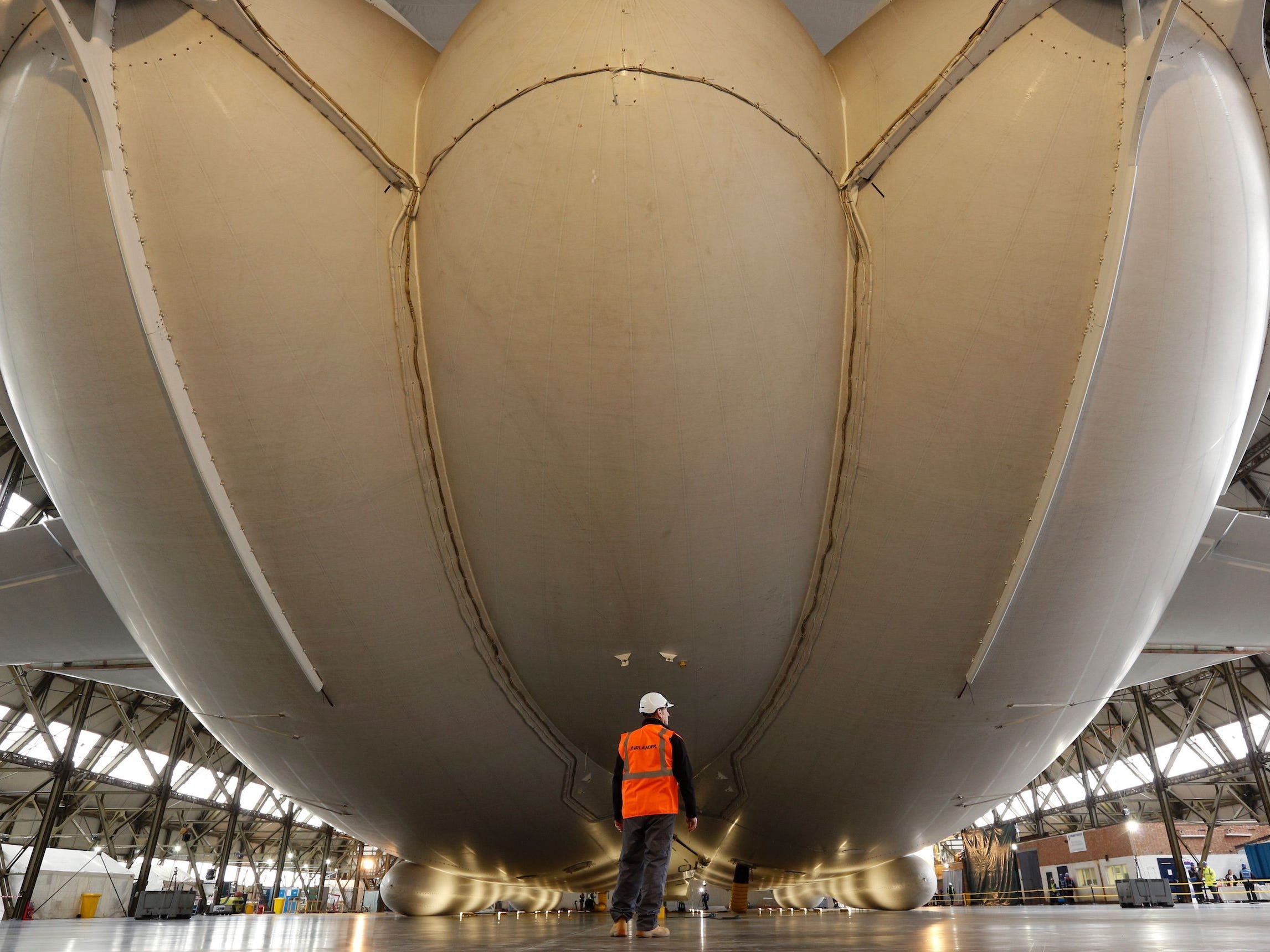 the exterior of the Airlander 10 in a hangar with someone walking by