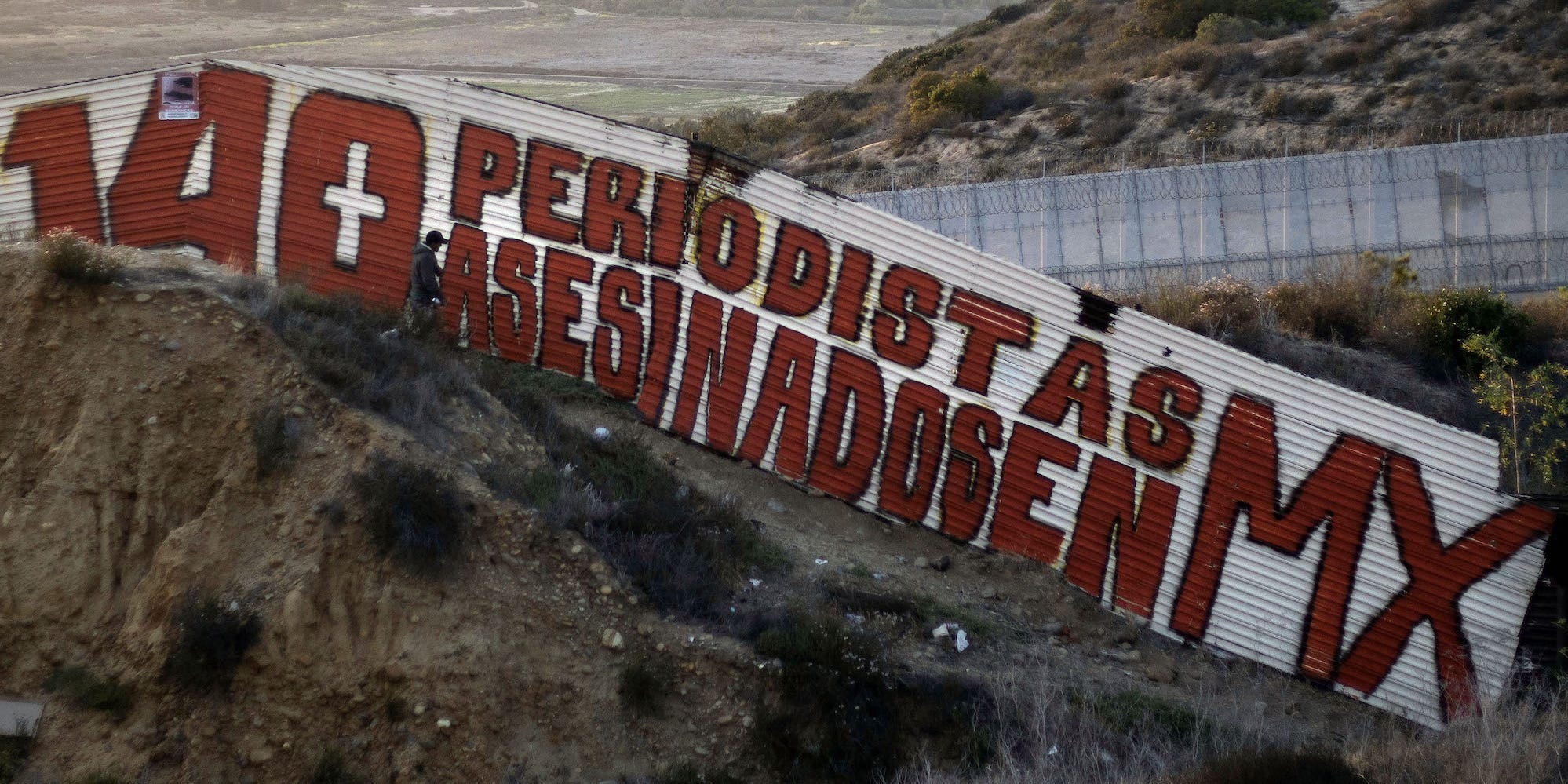 Border wall sign protesting violence against journalists in Mexico