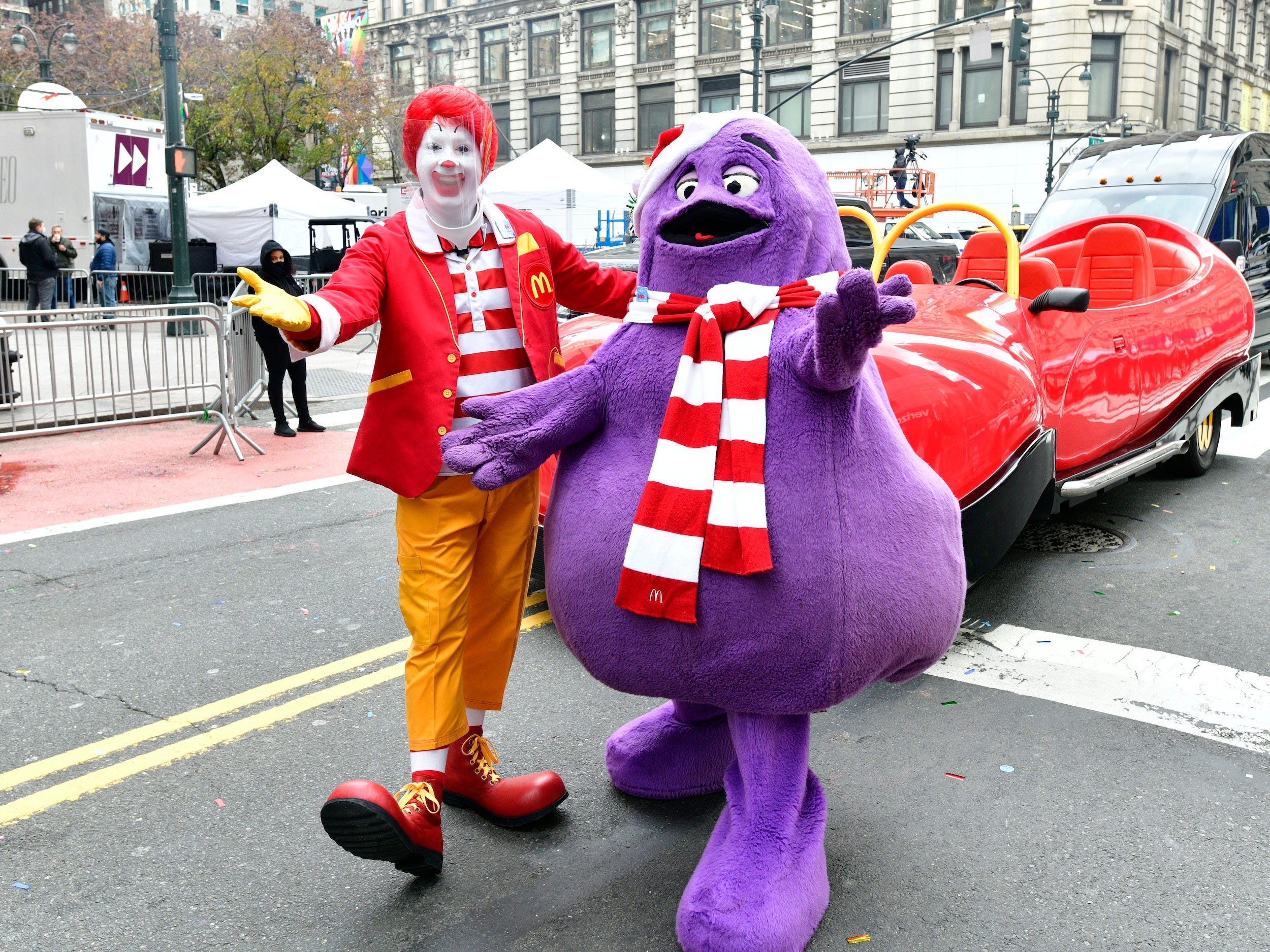 Ronald McDonald and Grimace with arms outstretched standing on street at Macy's parade