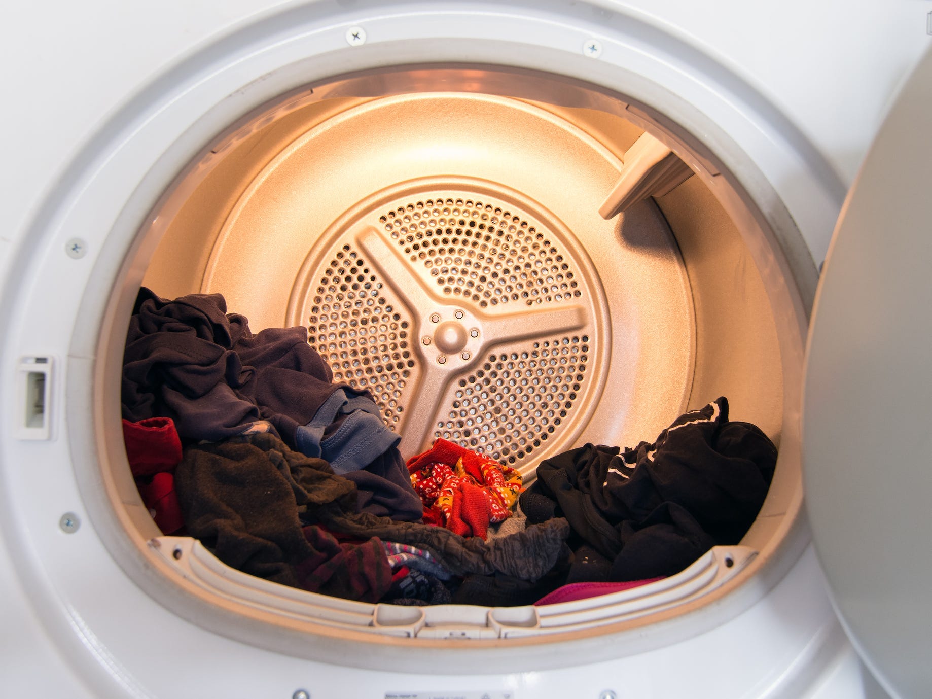 An open clothes dryer with clothes inside