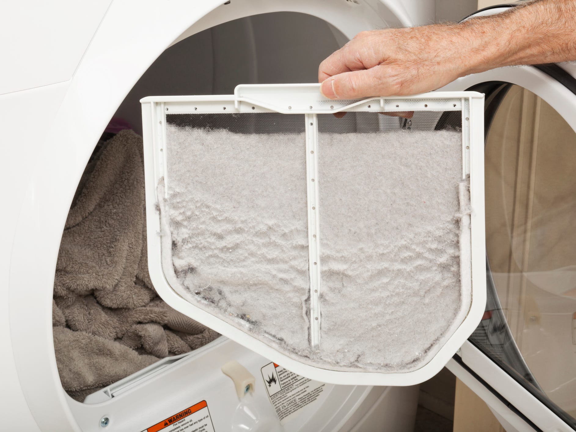 A person holding up a dryer lint trap full of lint