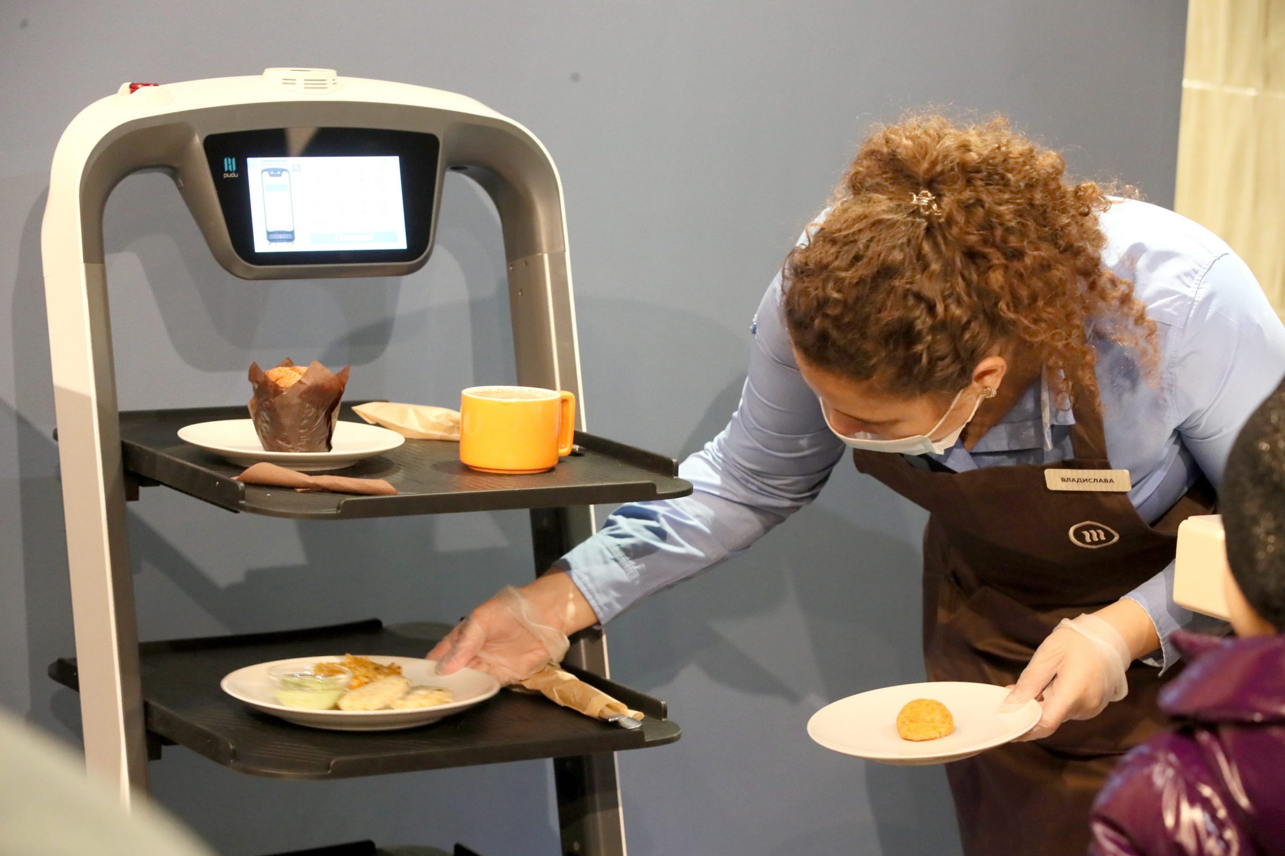 A waitress puts plates on a tray of a robot waiter at a Shokoladnitsa coffee shop in Russia.