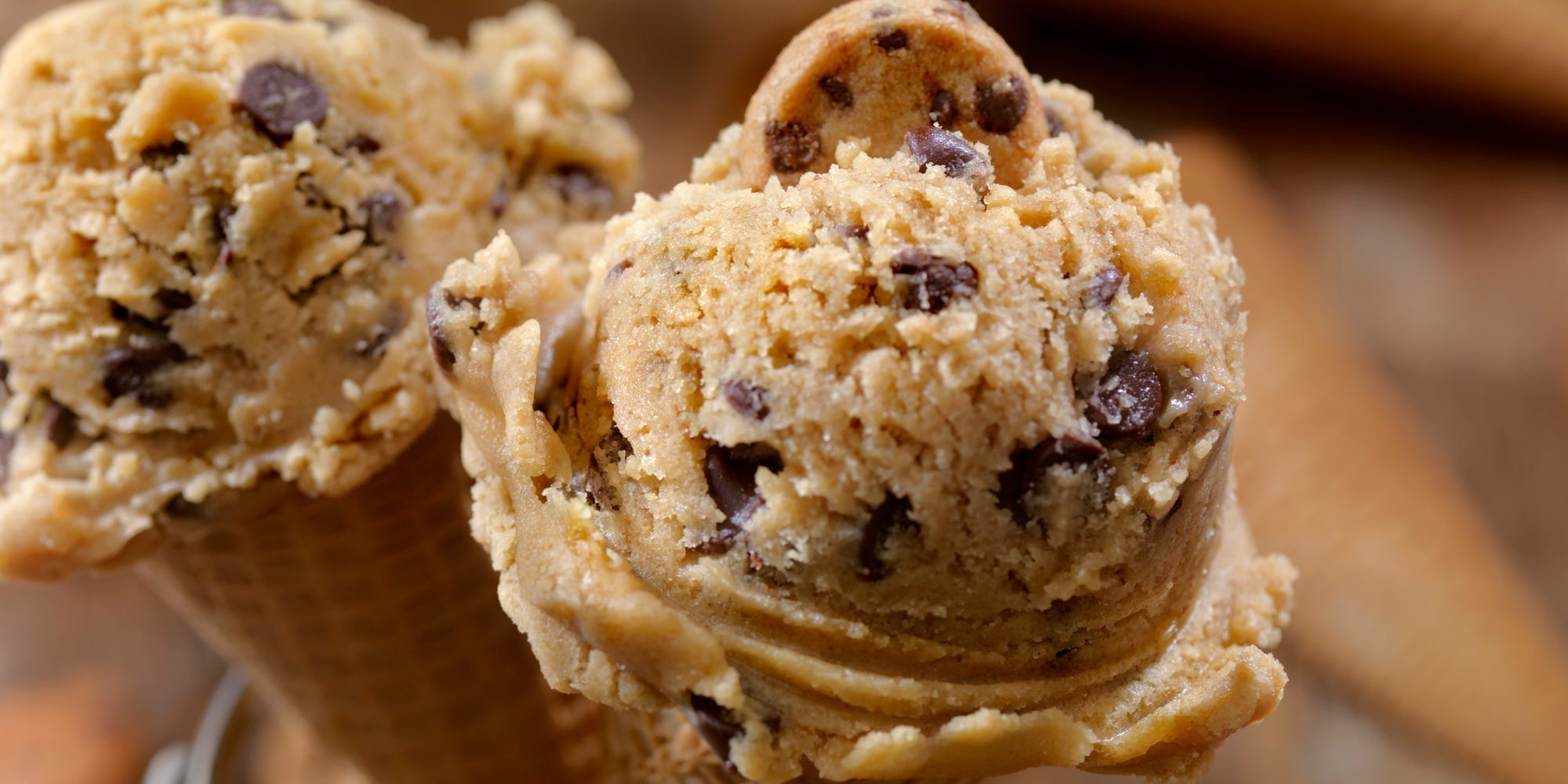 Two ice cream cones topped with big scoops of edible cookie dough instead of ice cream