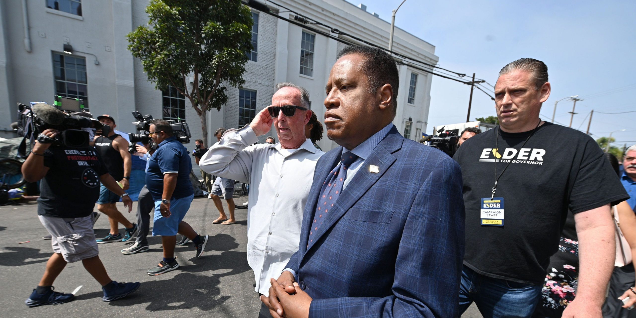 Conservative talk show host and gubernatorial recall candidate Larry Elder (C) walks along streets lined with tents of unhoused people, in the Venice neighborhood of Los Angeles, California, September 8, 2021 ahead of the special recall election. - The recall election, which will be held on September 14, 2021, asks voters to respond two questions: whether Governor Gavin Newsom, a Democratic, should be recalled from the office of governor, and who should succeed Newsom if he is recalled. Forty-six candidates, including nine Democrats and 24 Republicans, are looking to take Newsom's place as the governmental leader of California.