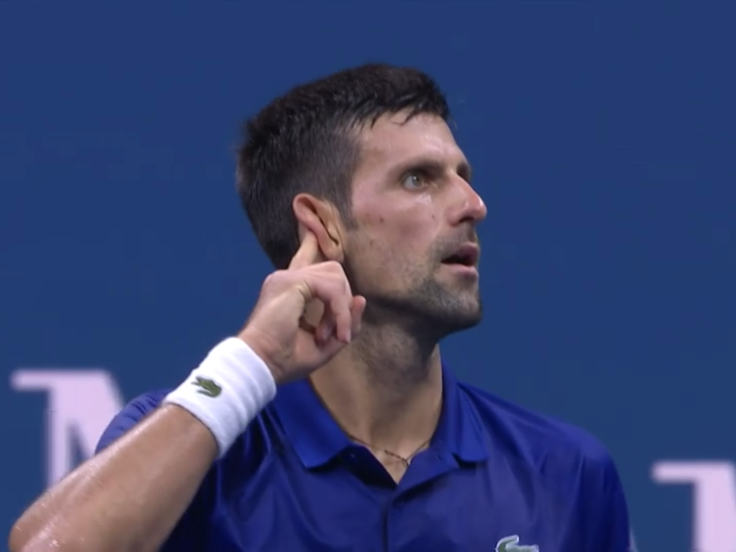 Novak Djokovic raises his finger to his ear at the US Open