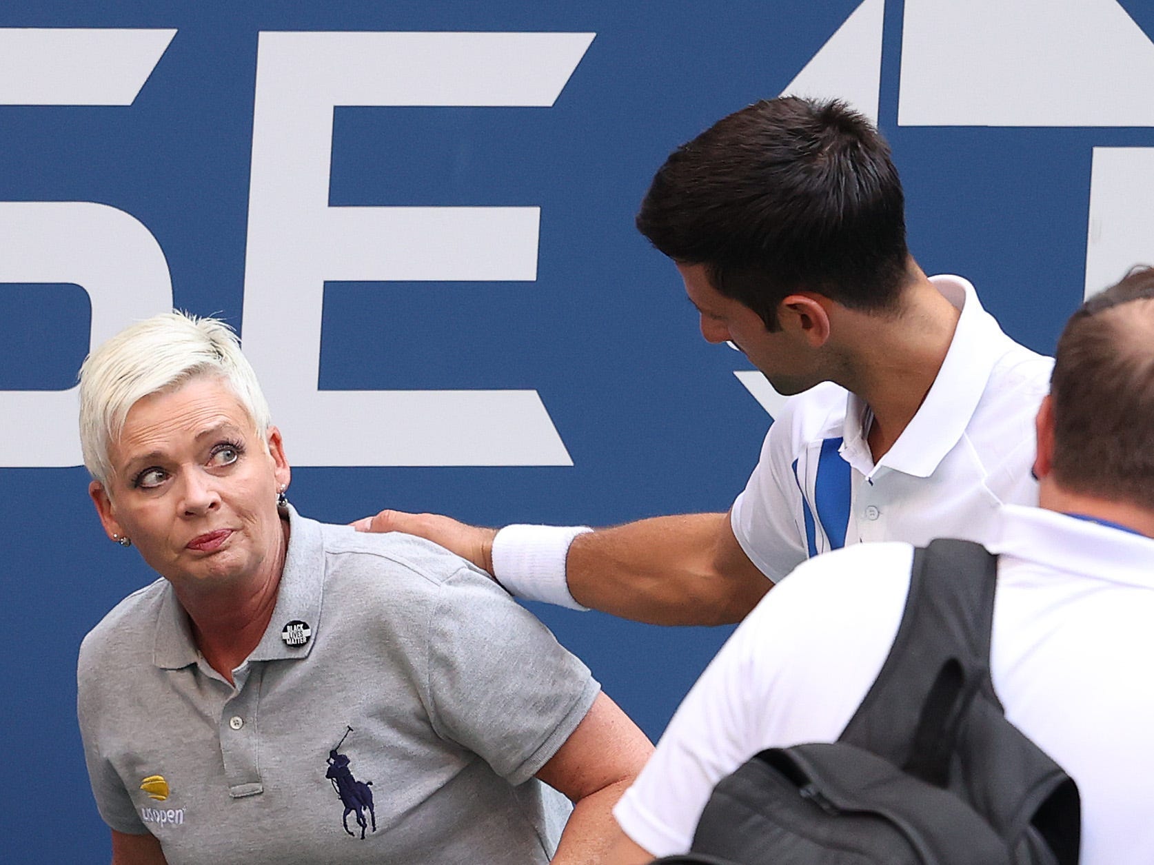 Novak Djokovic tends to a line judge Laura Clark who was hit with the ball