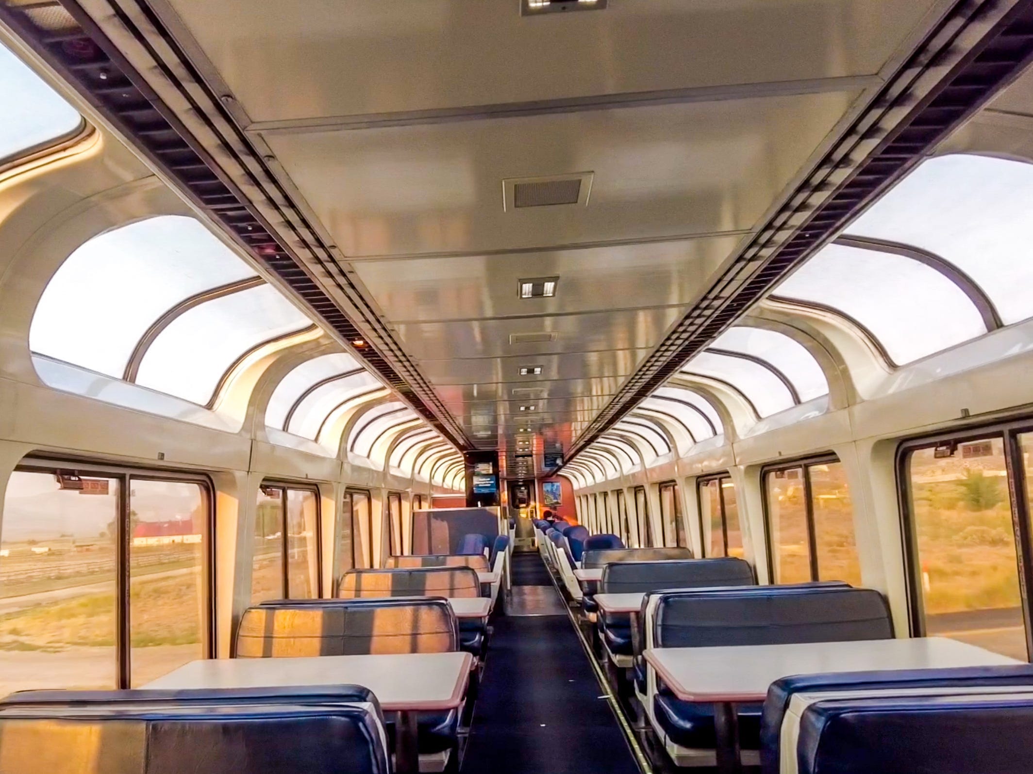 A view of the Amtrak observation car, which is full of windows and blue seats