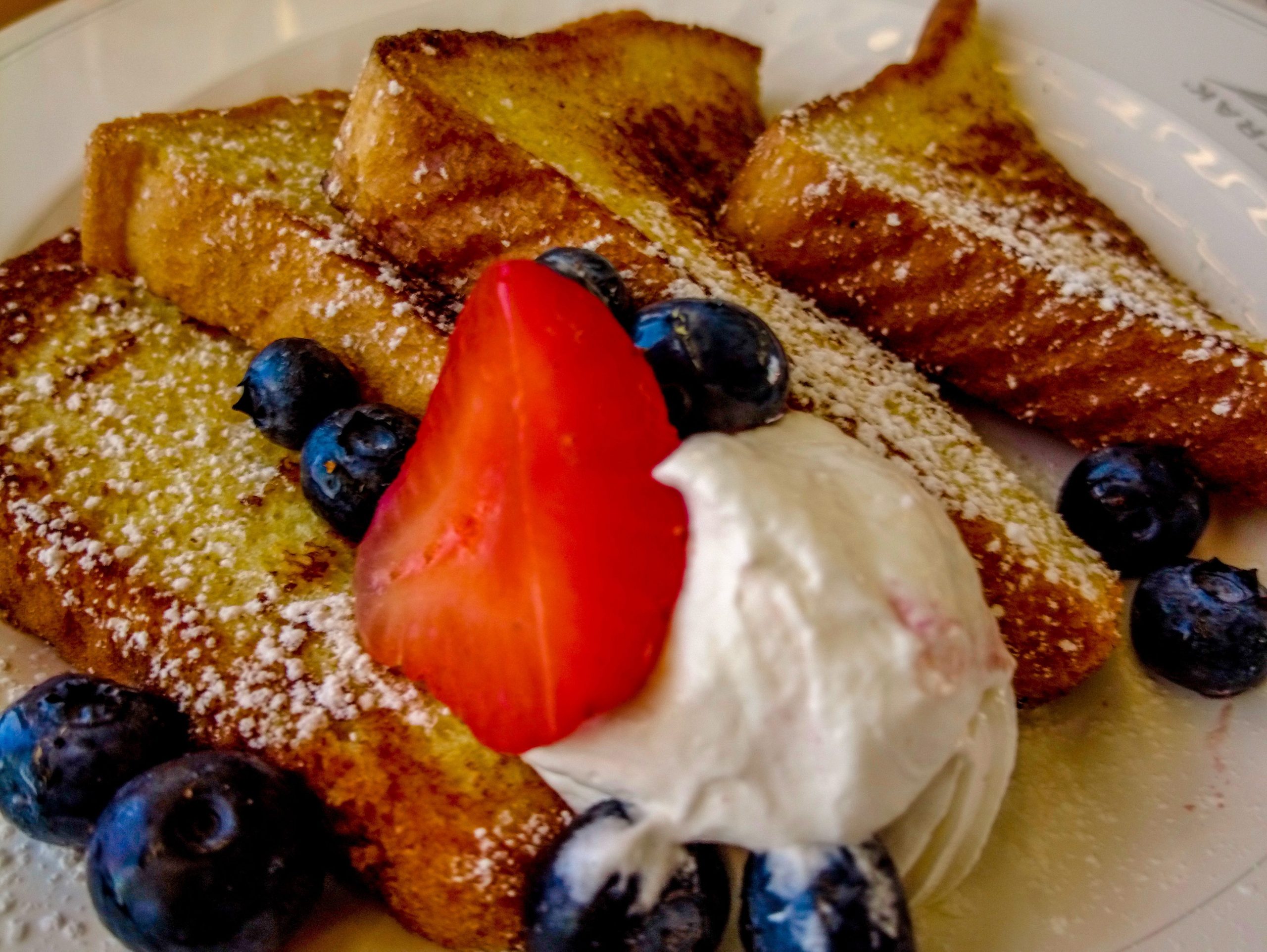 French toast with berries and cream on a white plate