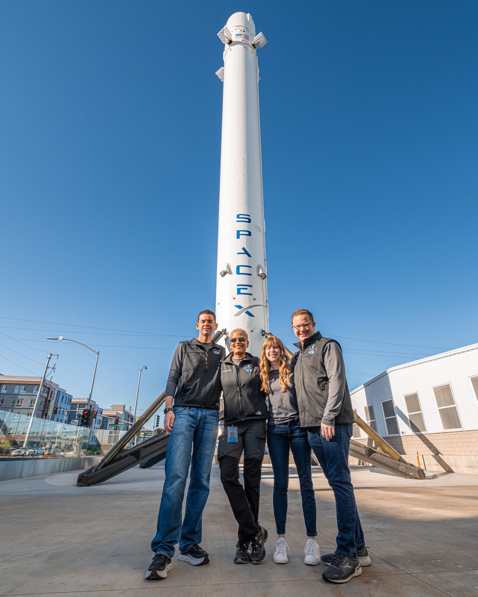 inspiration4 crew pose in front of display falcon 9 rocket