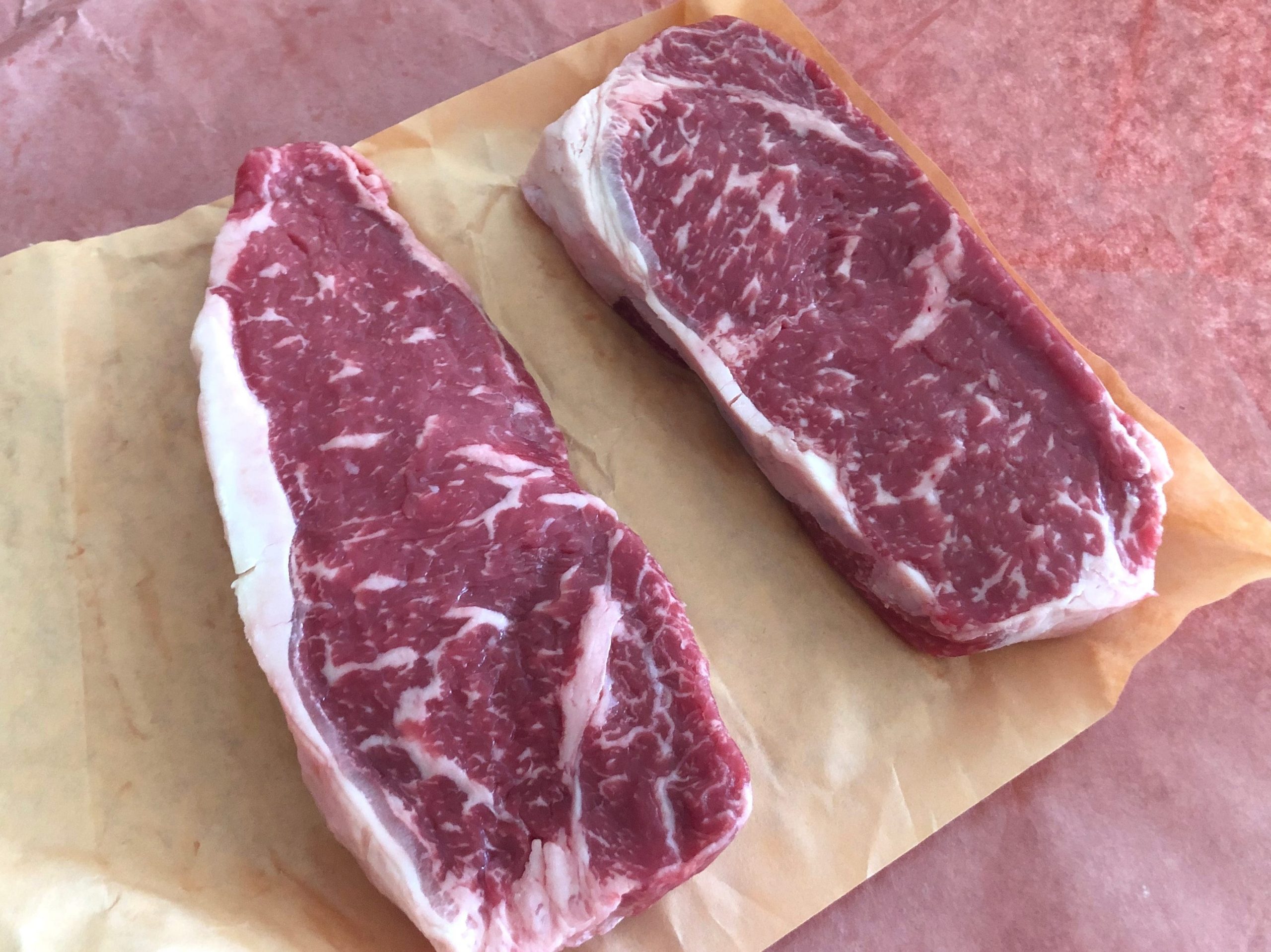 Two raw New York strip steaks.