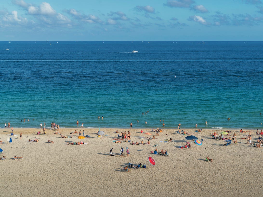 Tourists sunbathing on beach - stock photo