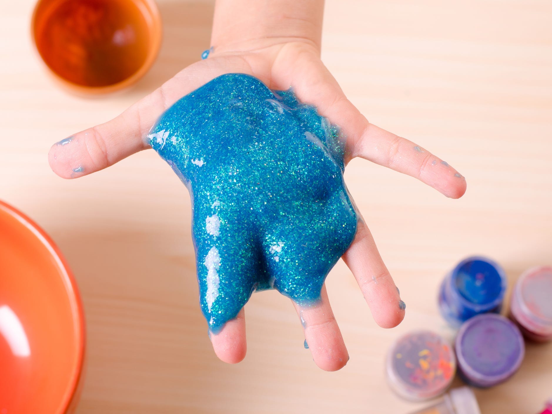 A kid holding glittering blue slime.