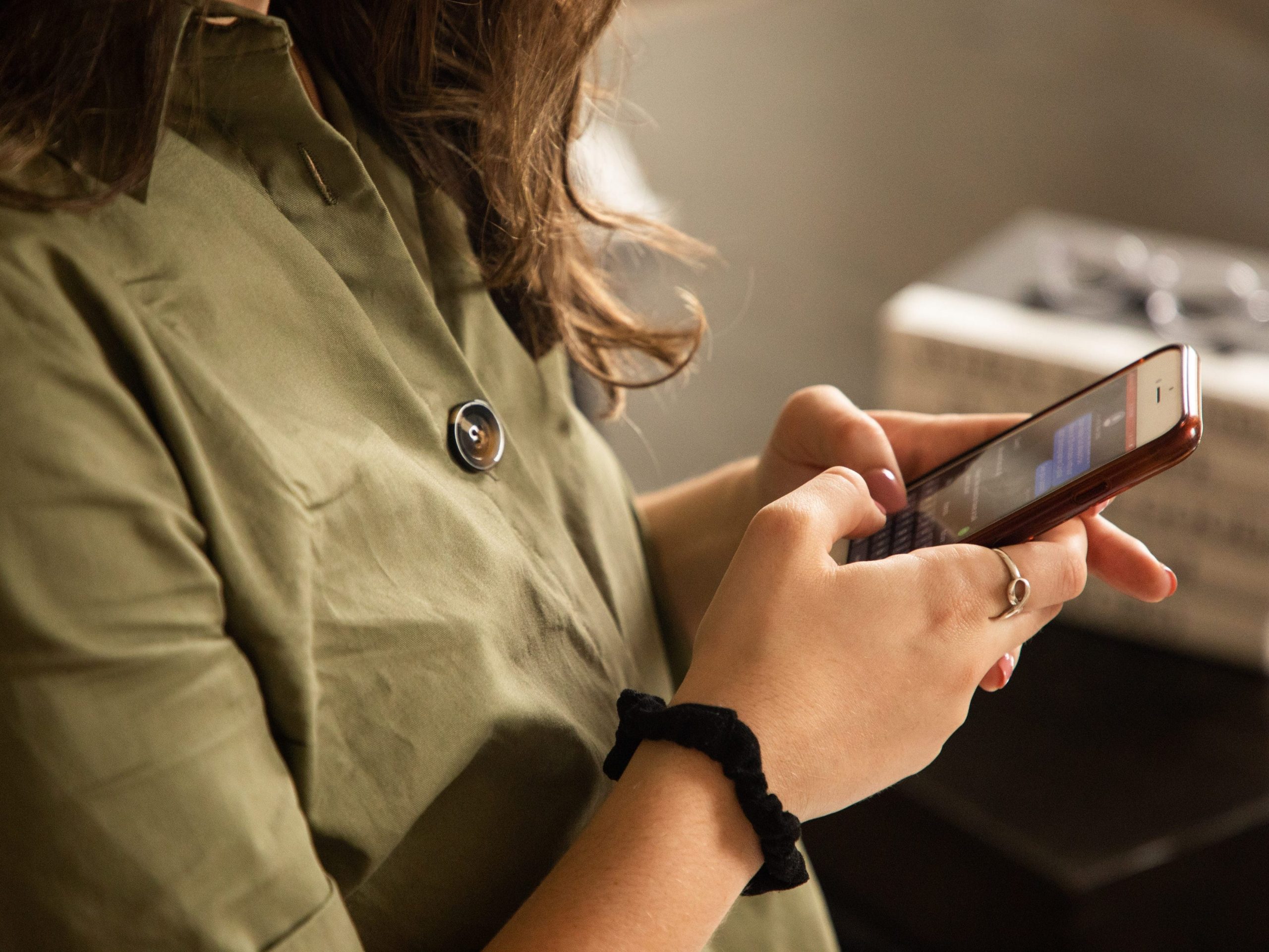 A woman uses both thumbs to text on her phone.