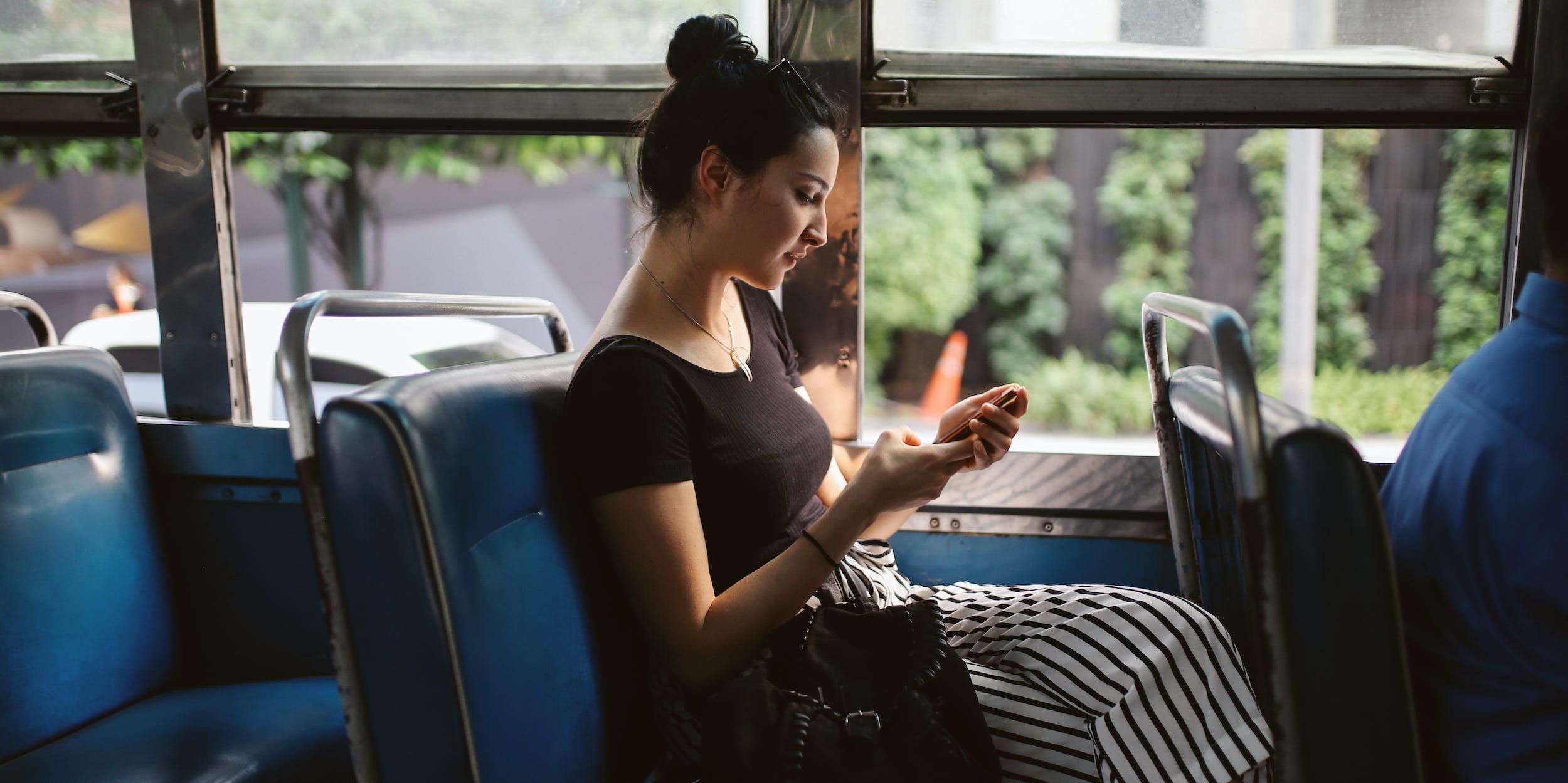 commuter sitting on bus looking at phone