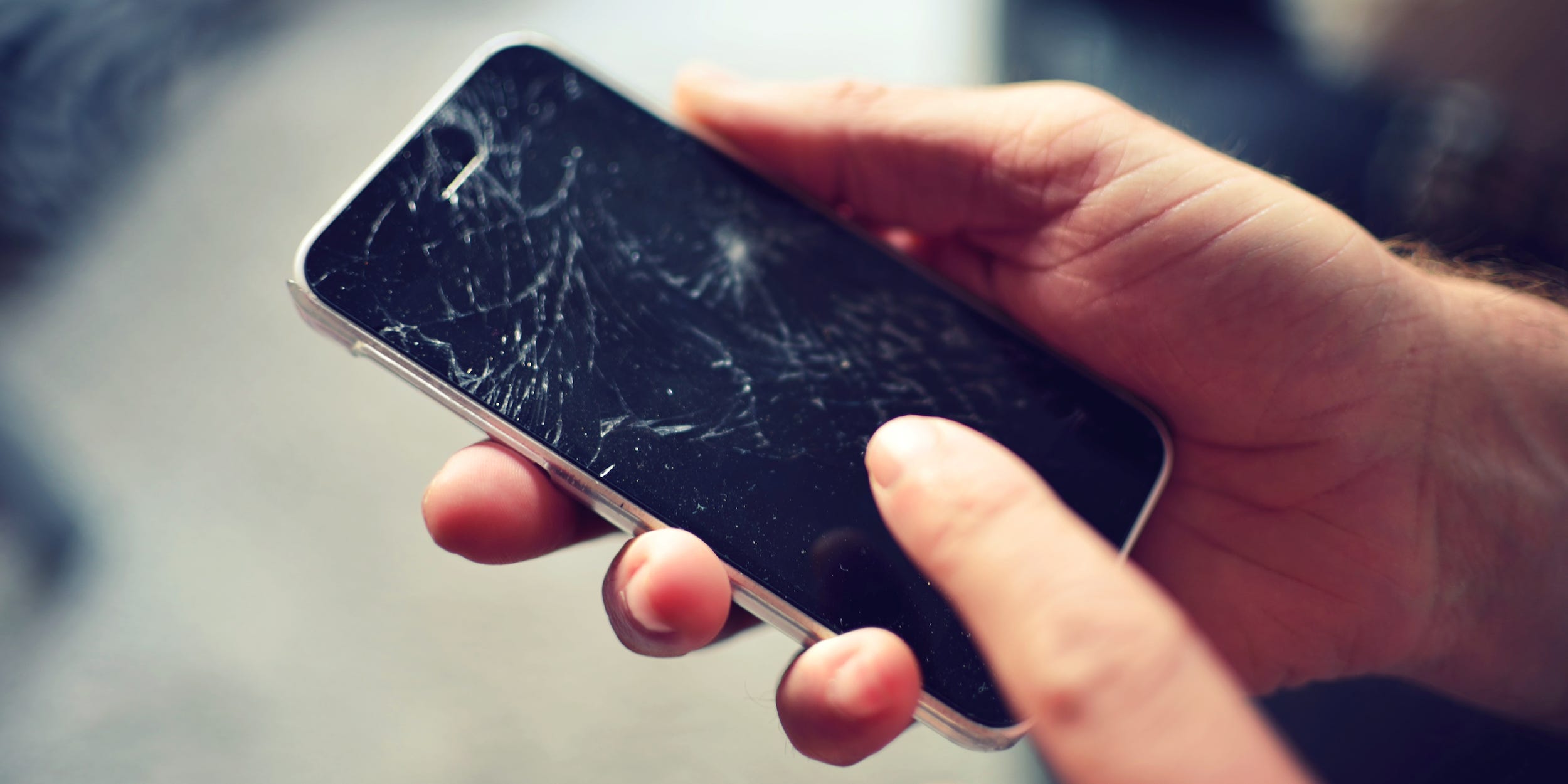 hands touching a smartphone with a broken cracked screen