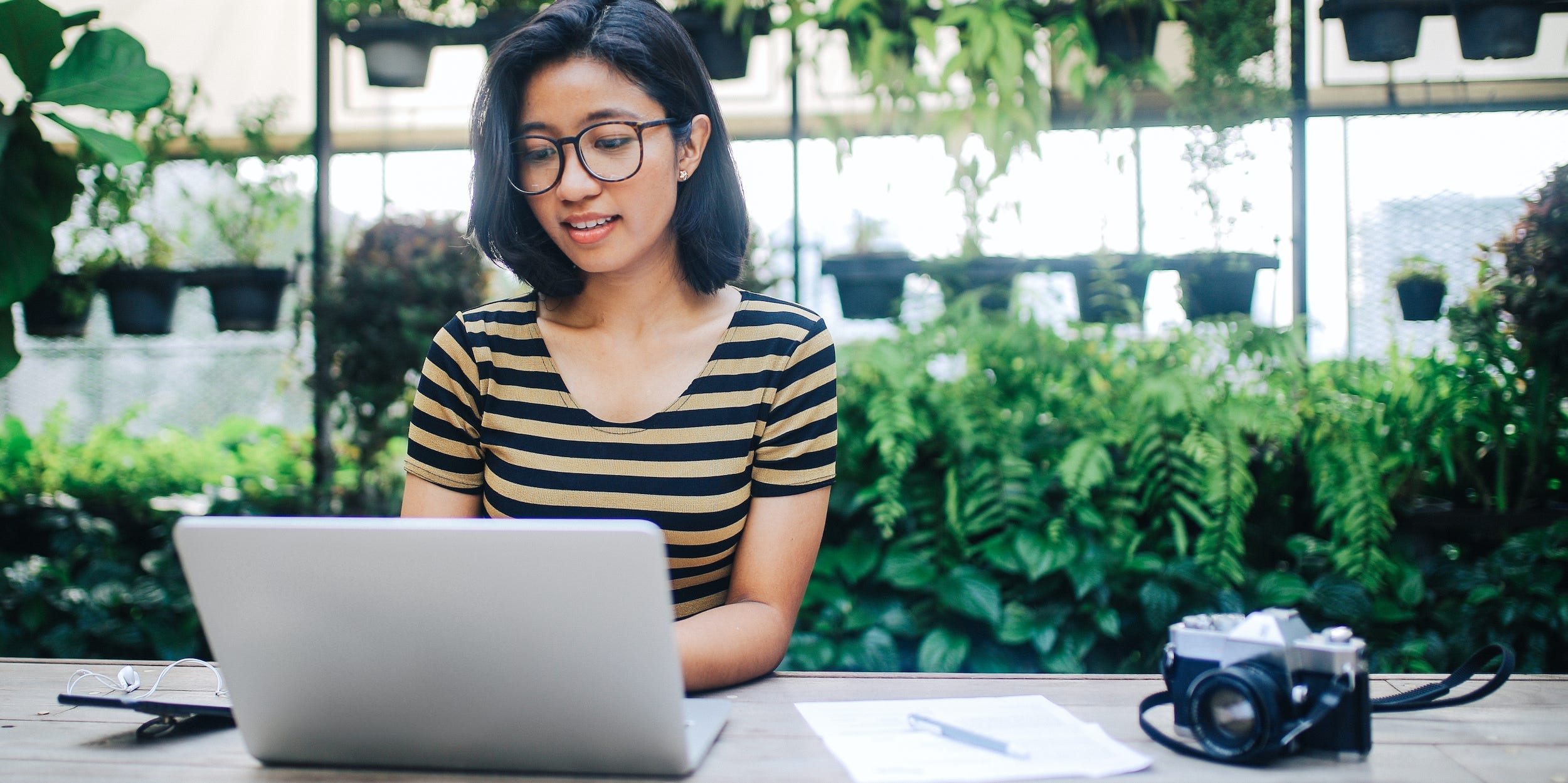 Photographer using laptop at desk next to camera