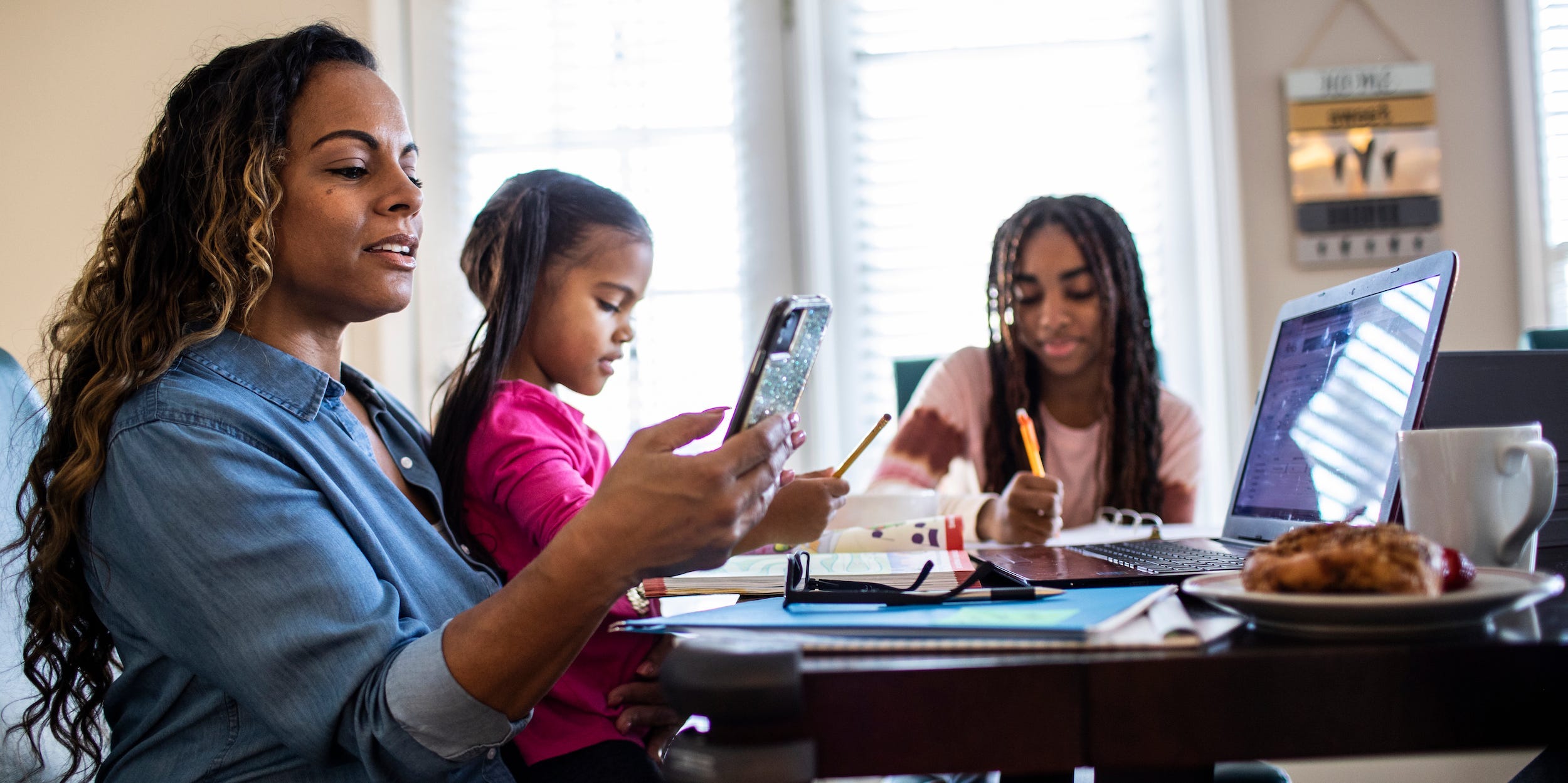 family using internet on phone and laptop at home kitchen table