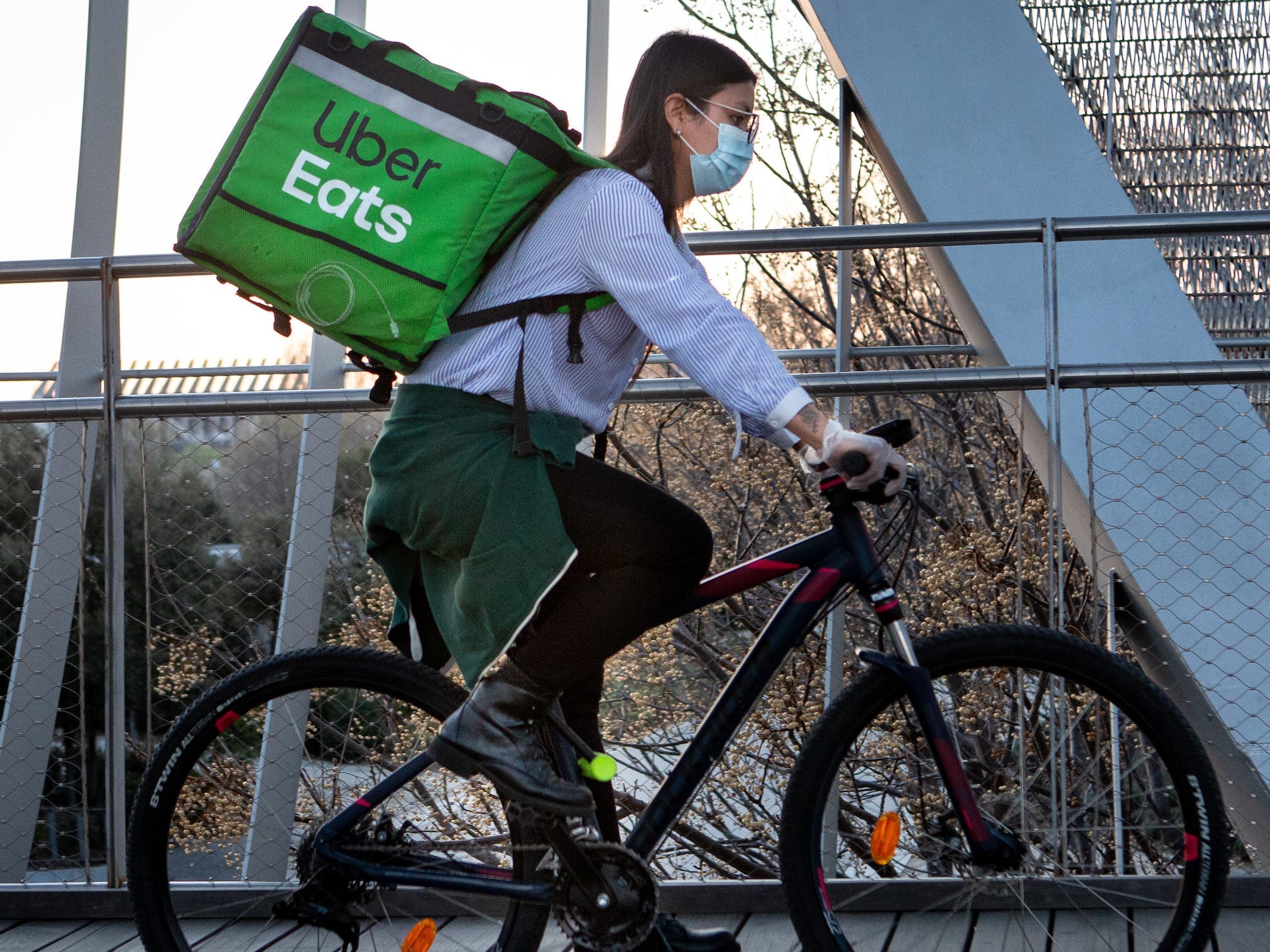 An Uber Eats delivery bike rider wears face mask as a precaution against transmission of the coronavirus at Madrid Rio park on March 14, 2020 in Madrid, Spain. Today known cases of Covid-19 in Madrid are 2,940, while there are 86 reported deaths. The cases in Spain are 5,867 people infected of coronavirus and 135 deaths. The Spanish Government has declared the state of emergency to contain the spread of the virus. All businesses which are not of prime interest, such as grocery stores and pharmacies will have to close temporarily.