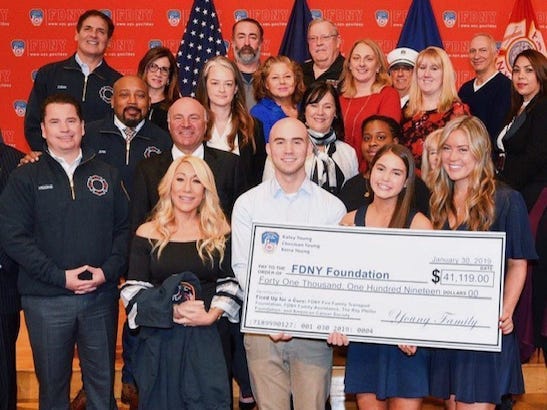 Kaley Young, Keira Young, and Christian Young hold a large check for $41,119 to the FDNY Foundation and pose with firefighters and the cast of 'Shark Tank.'