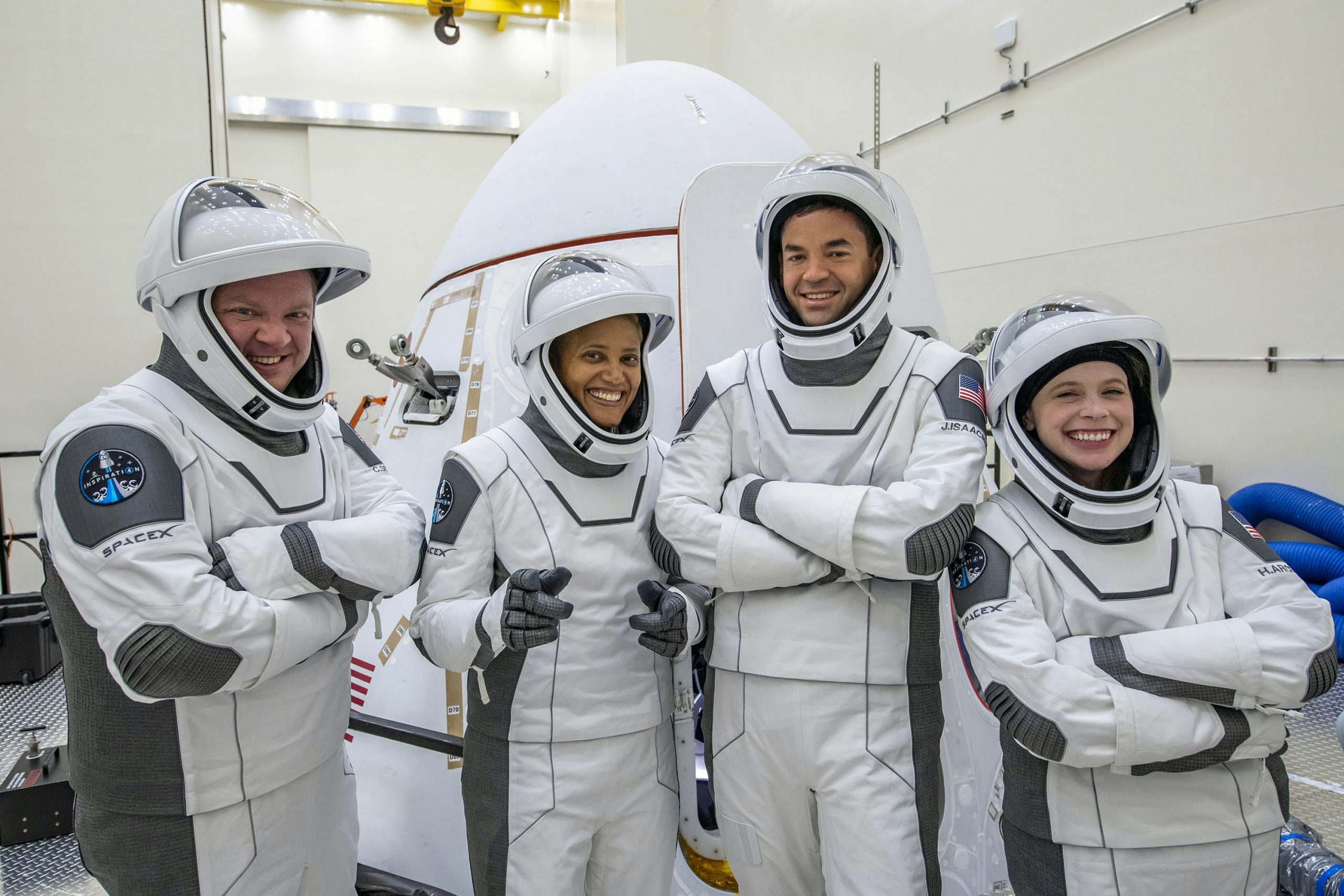 inspiration4 crew members pose in white grey spacex spacesuits in front of crew dragon spaceship