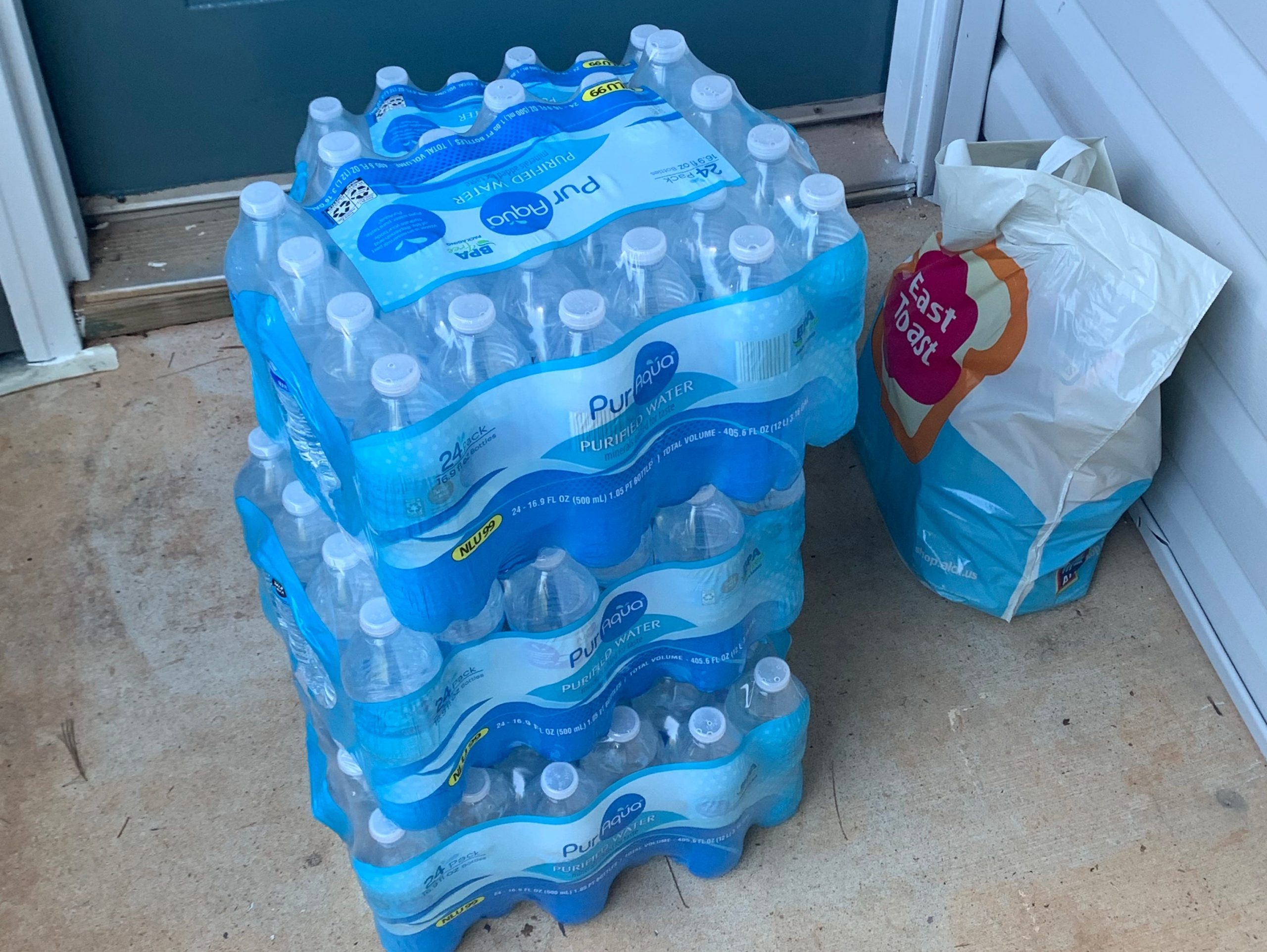 A stack of cases of water bottles outside of someone's door