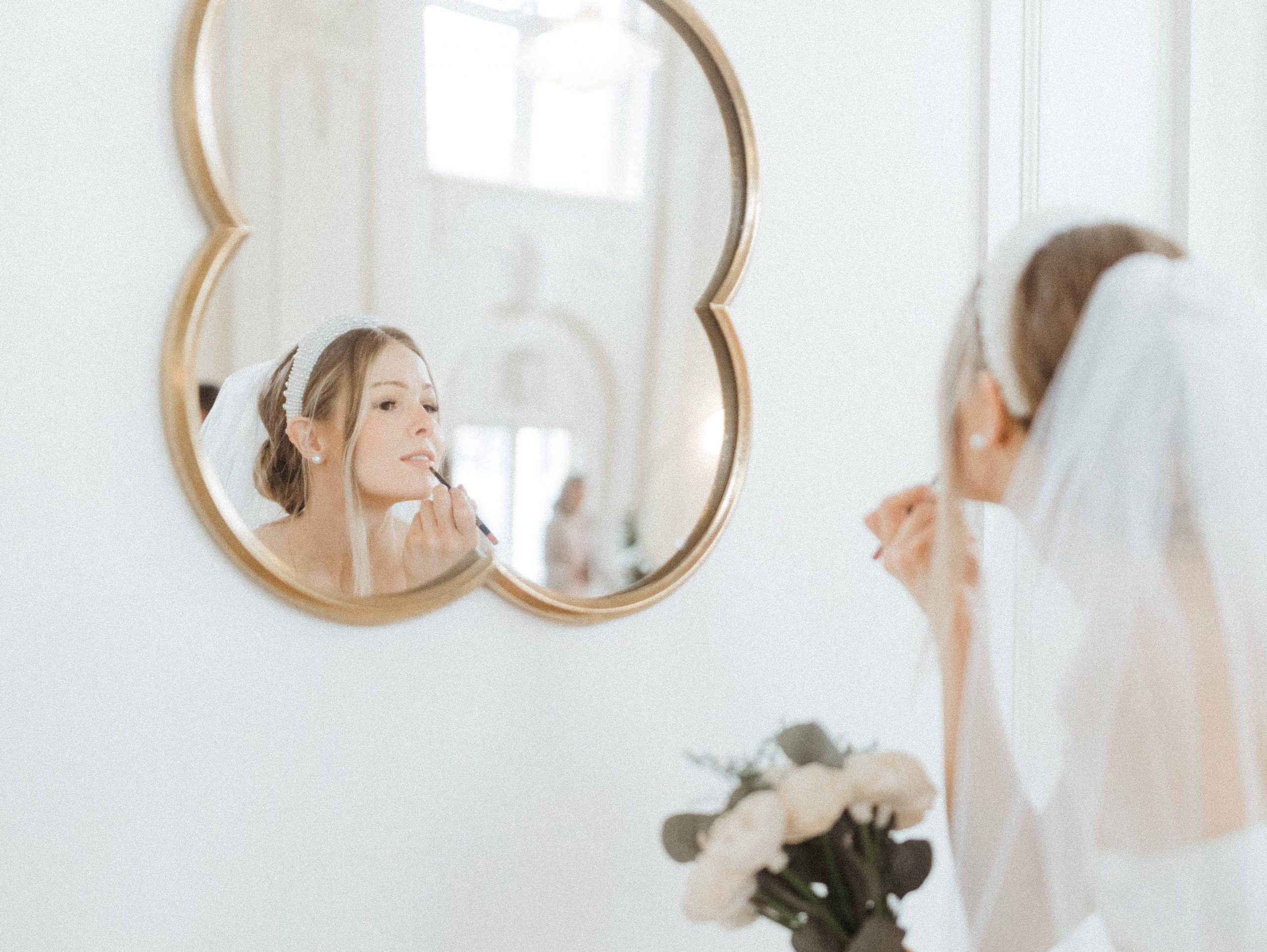 bride using a mirror to get ready for her wedding day