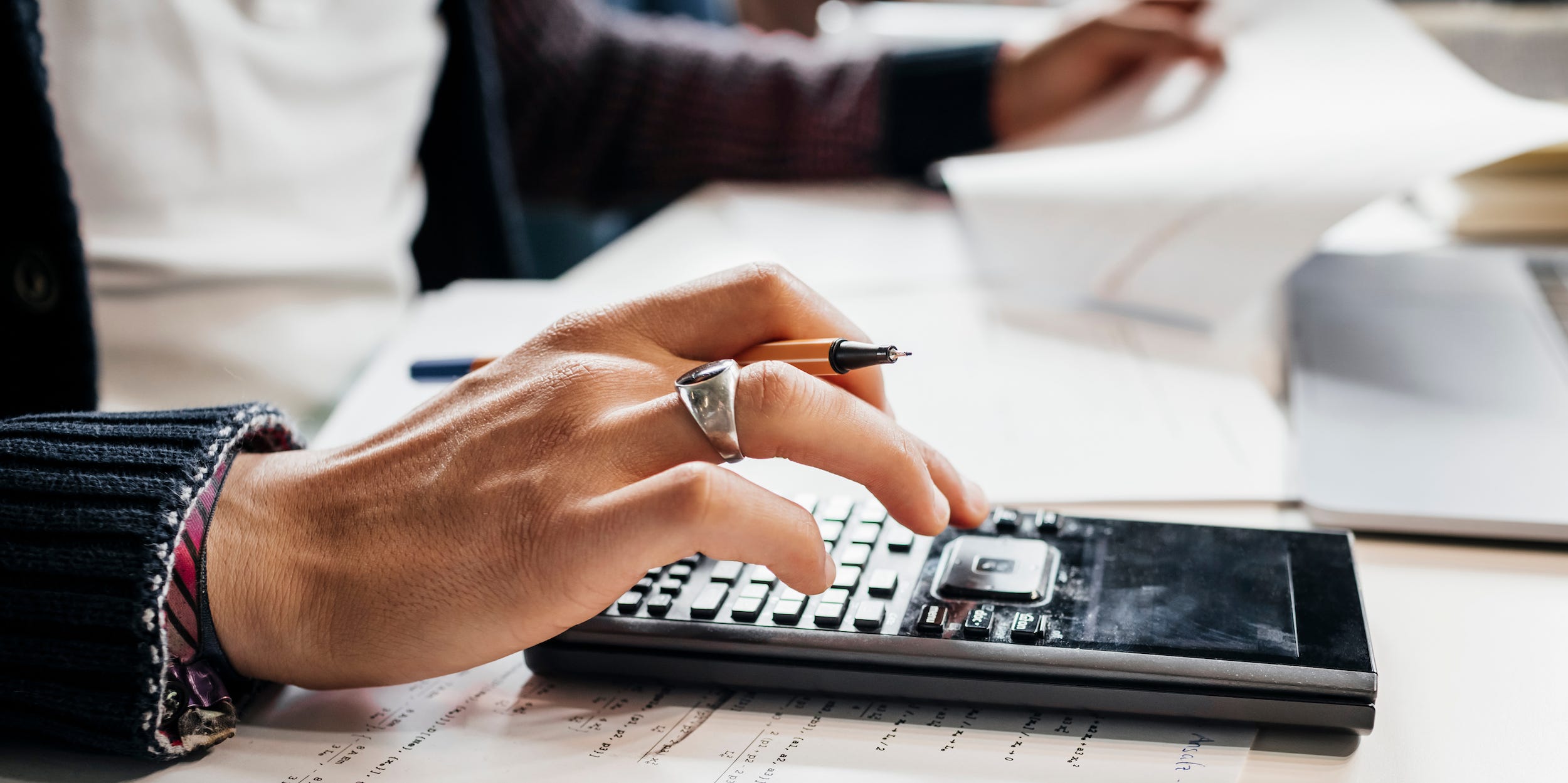 Close up of a person using a calculator while studying.