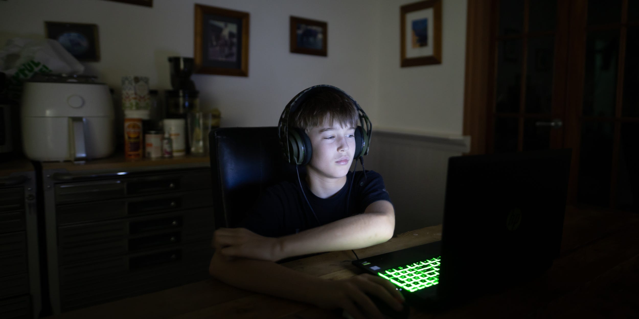 teen looking at computer screen in room at night with headphones on