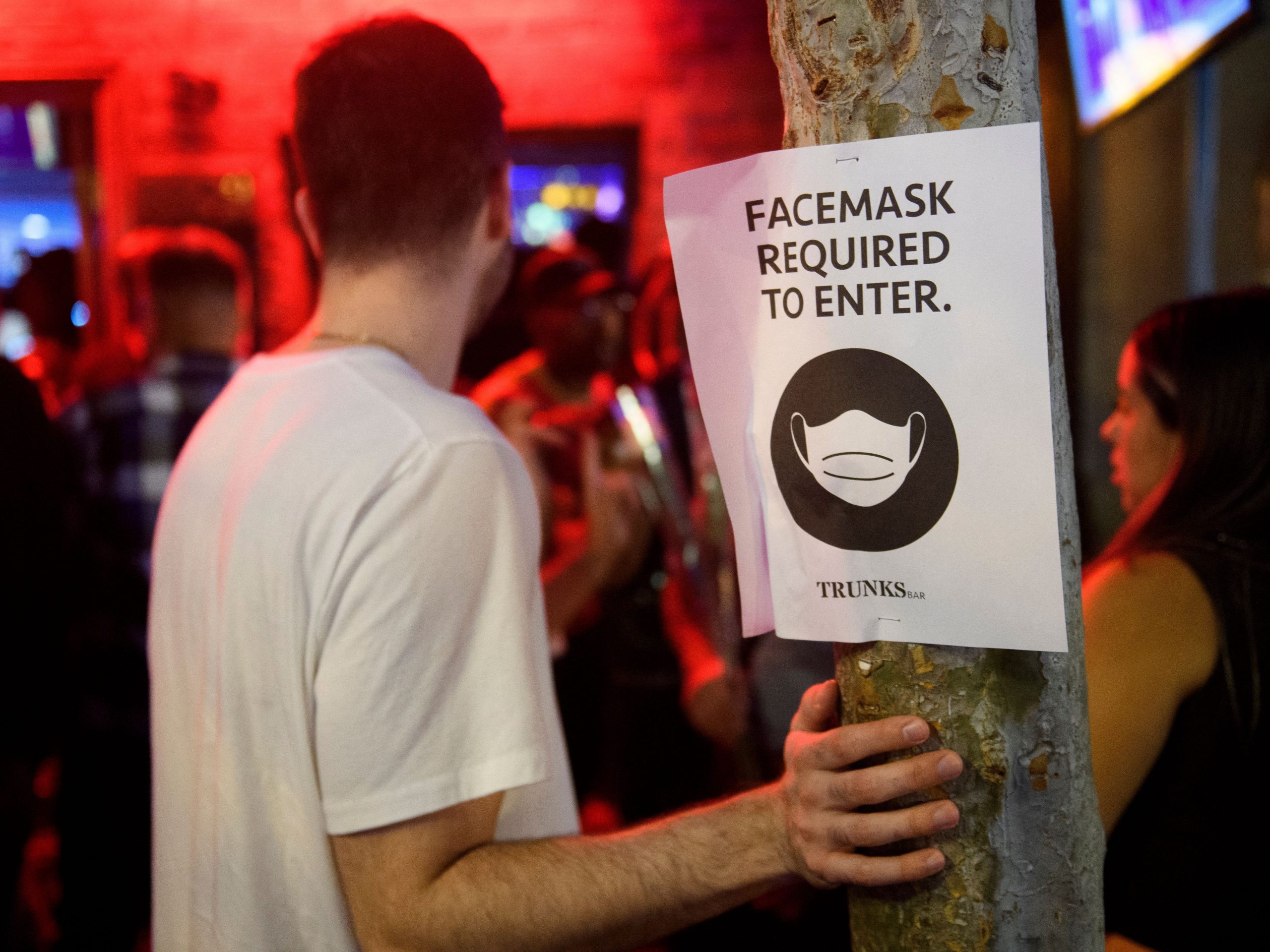 Face mask signage is displayed outside the Trunks bar after midnight early Sunday morning on July 18, 2021 in West Hollywood, California