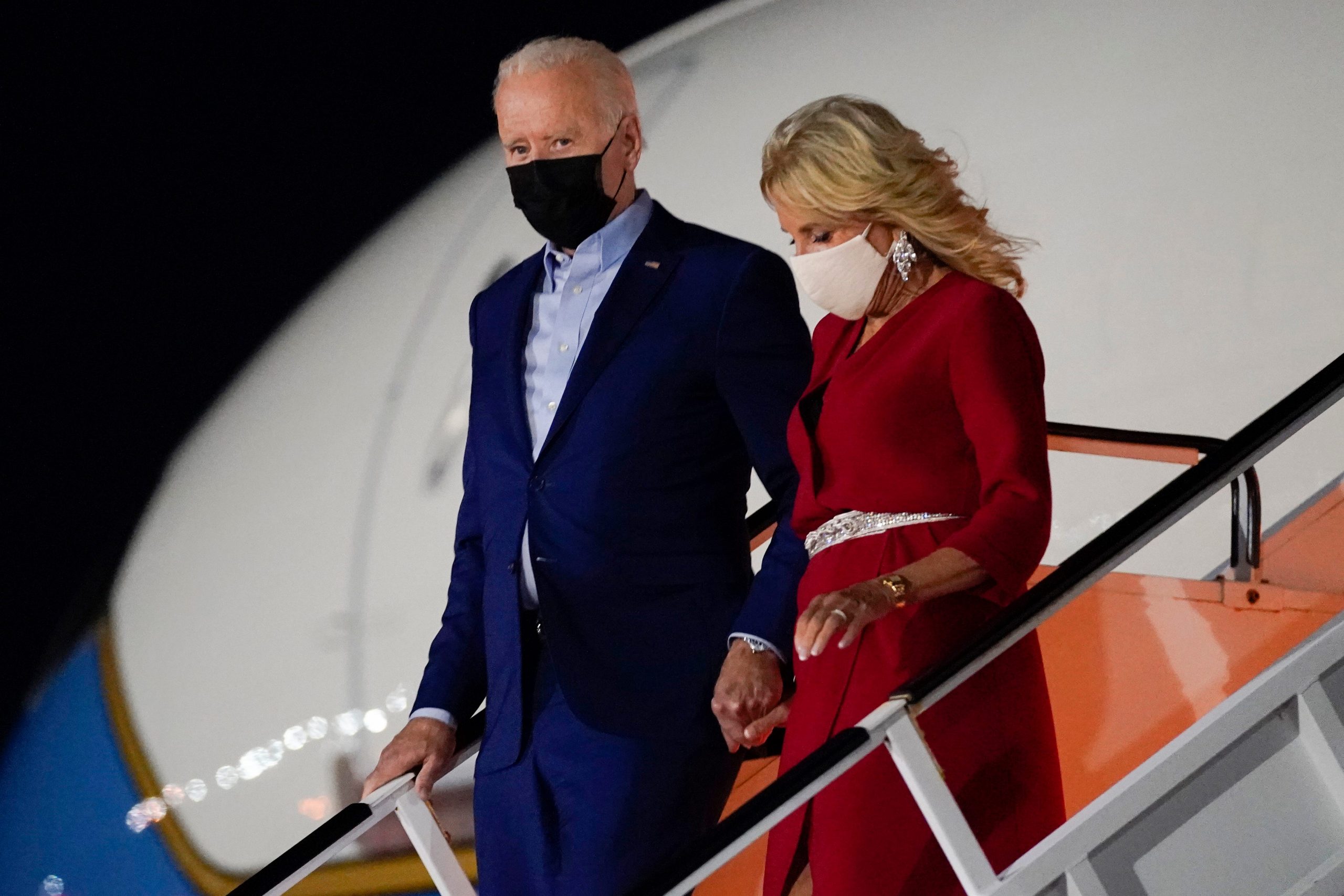 President Joe Biden holds first lady Dr. Jill Biden's hand as they exit Air Force One