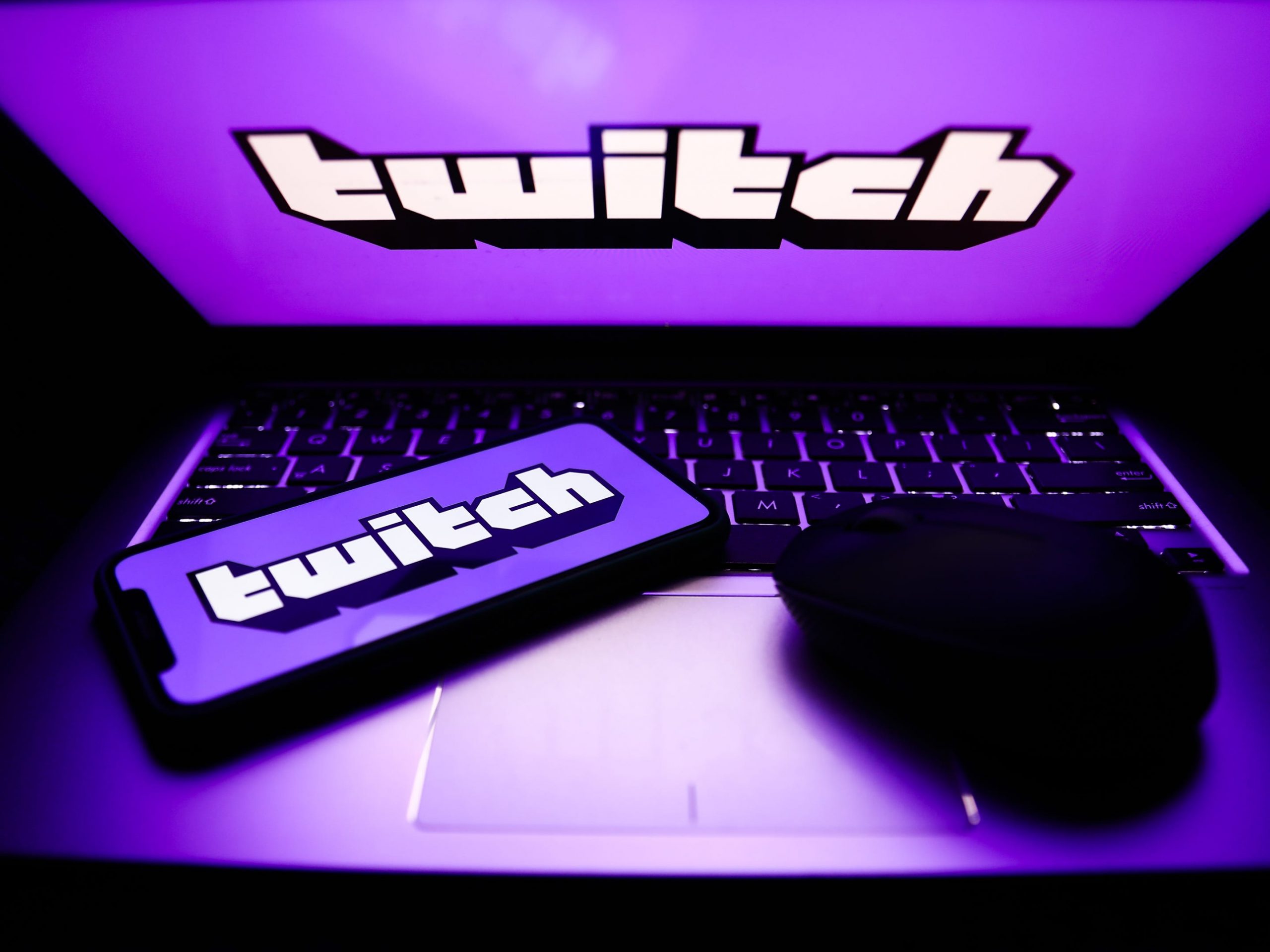 Twitch logos are seen displayed on a phone and a laptop screens in this illustration photo.