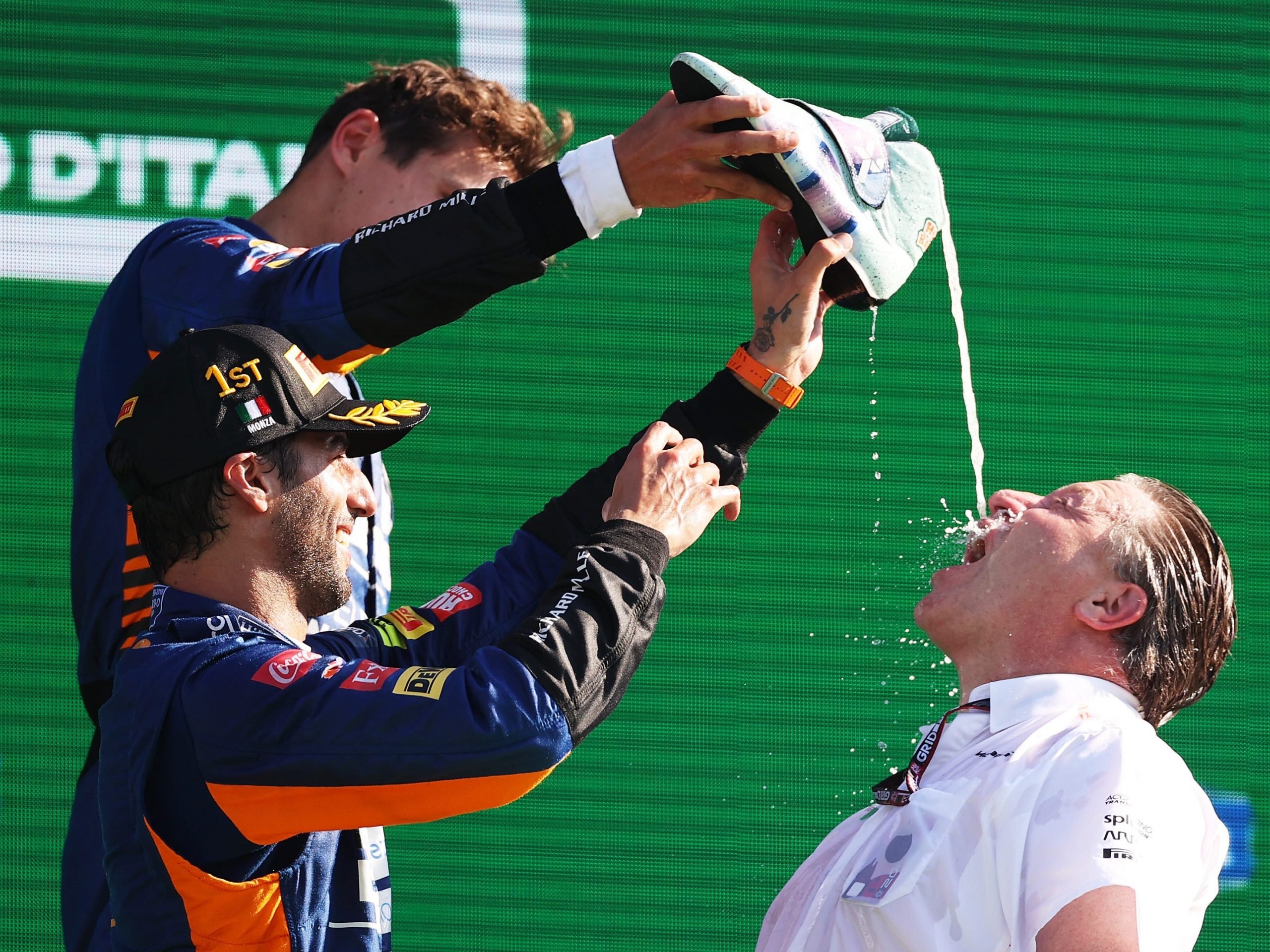 Lando Norris and Daniel Ricciardo pour champagne into Zac Brown's mouth