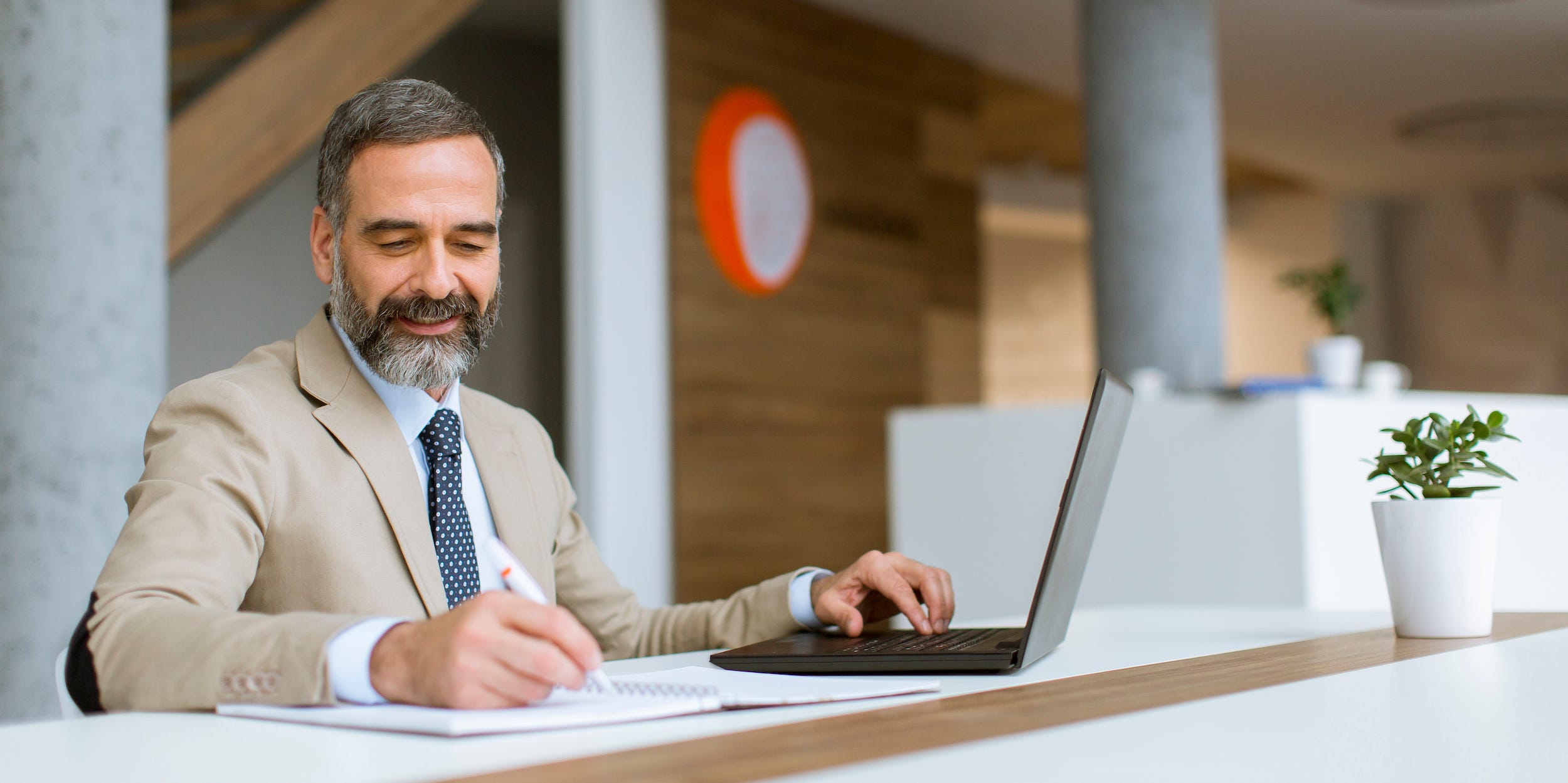 Senior businessman gray hair working on laptop in modern office.