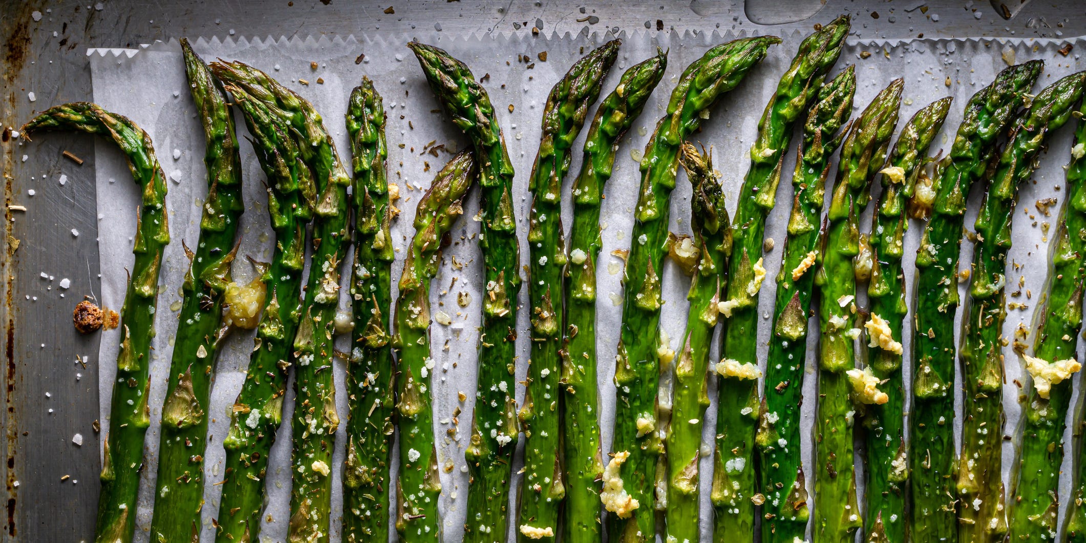 Roasted asparagus spears lined up on a baking tray