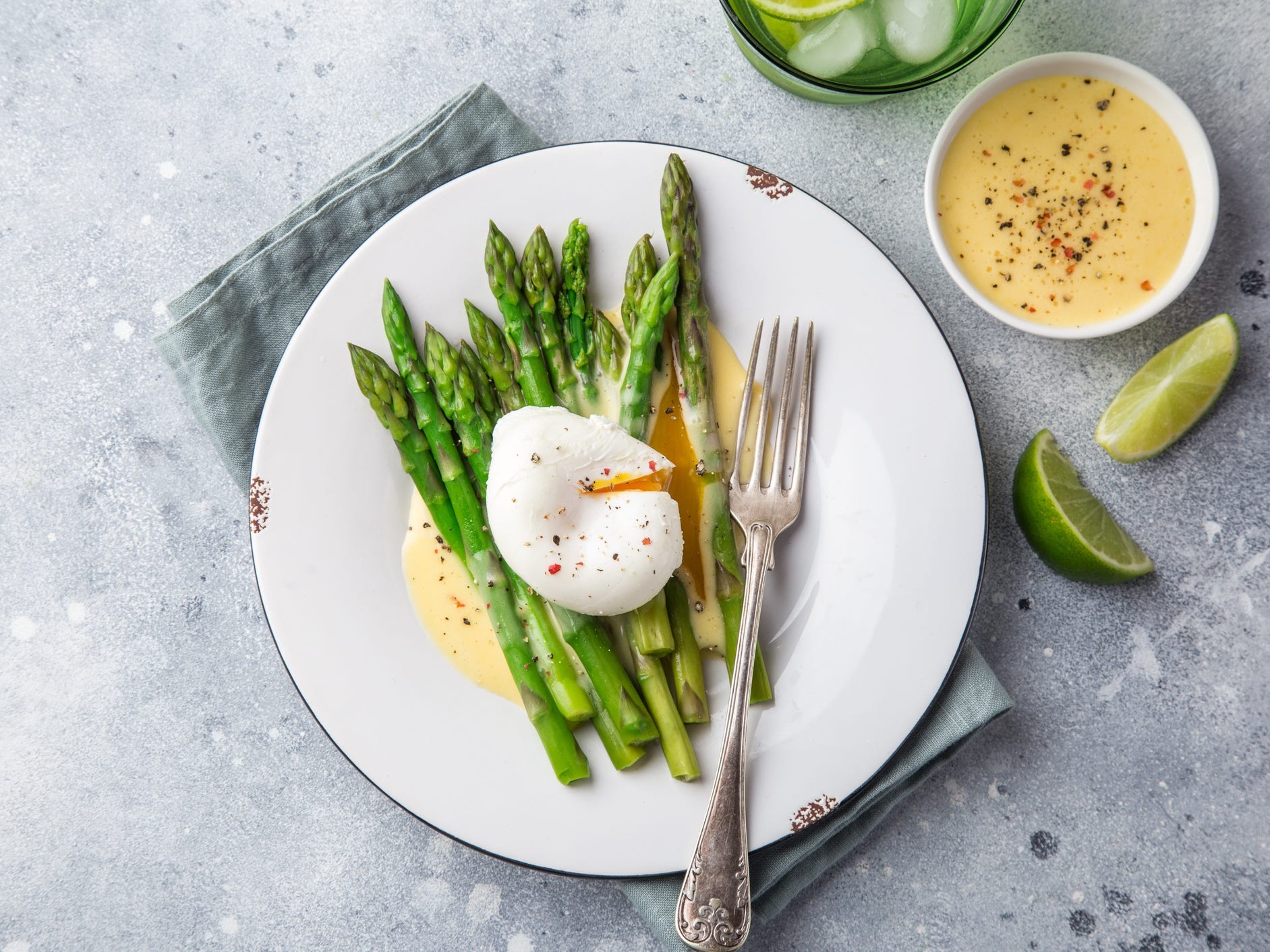 A plate of asparagus topped with hollandaise sauce and a poached egg