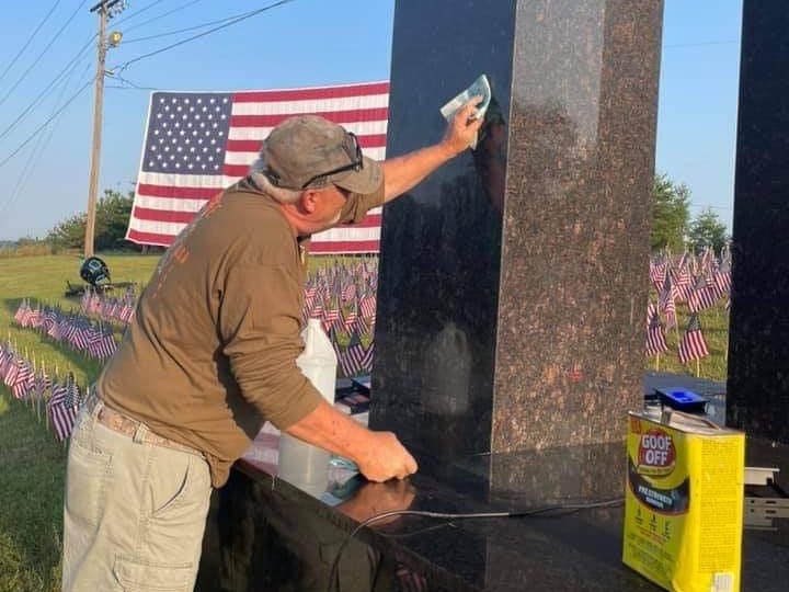 A man cleans off the spray paint from 9/11 memorial that was vandalized.