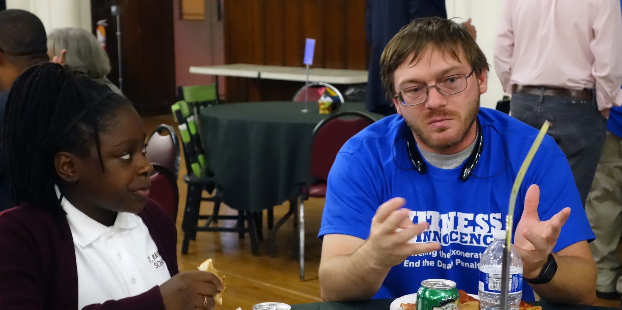 Damon Thibodeaux sits at a table while talking to a student.