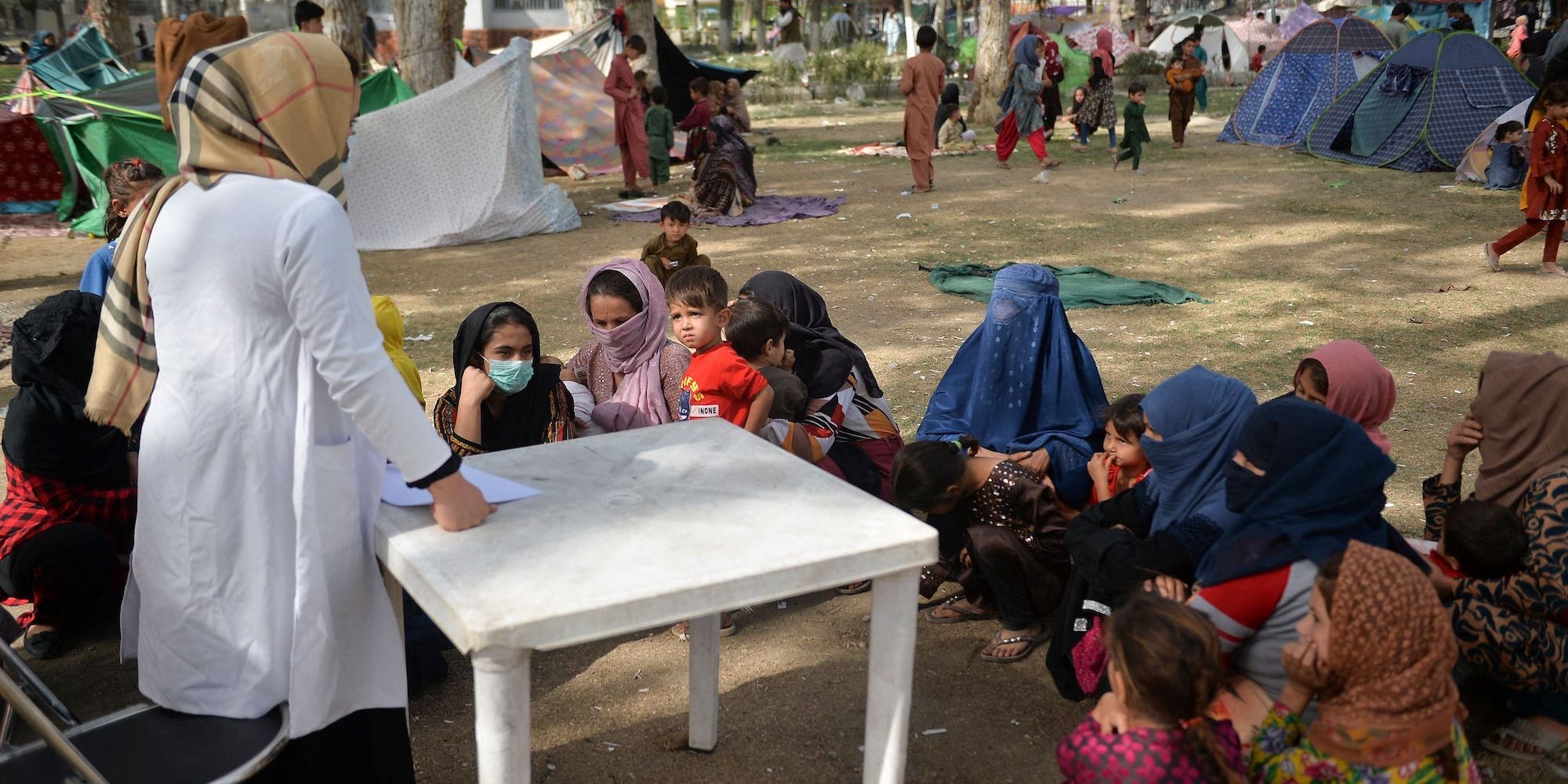 A medical staff talks with internally displaced children during a free medical camp at Shahr-e-Naw Park in Kabul on September 11, 2021.