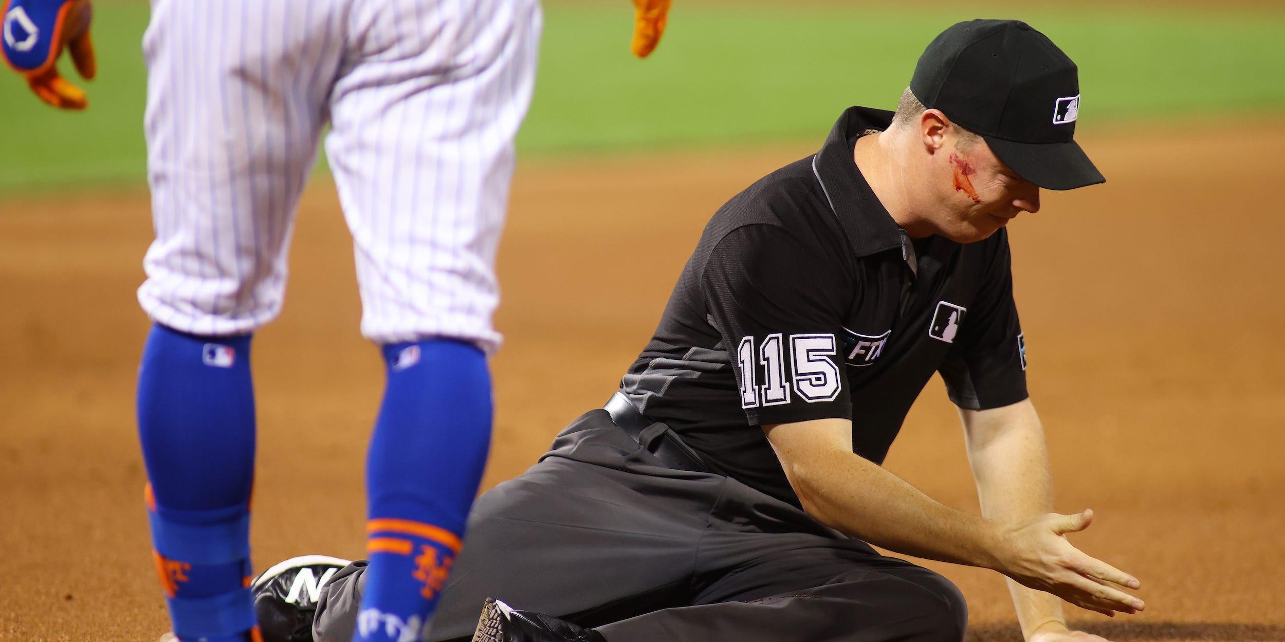 Umpire Junior Valentine reacts after getting hit in the face with the ball on a throw from Edmundo Sosa #63 of the St. Louis Cardinals in the second inning against the New York Mets at Citi Field on September 13, 2021 in New York City.