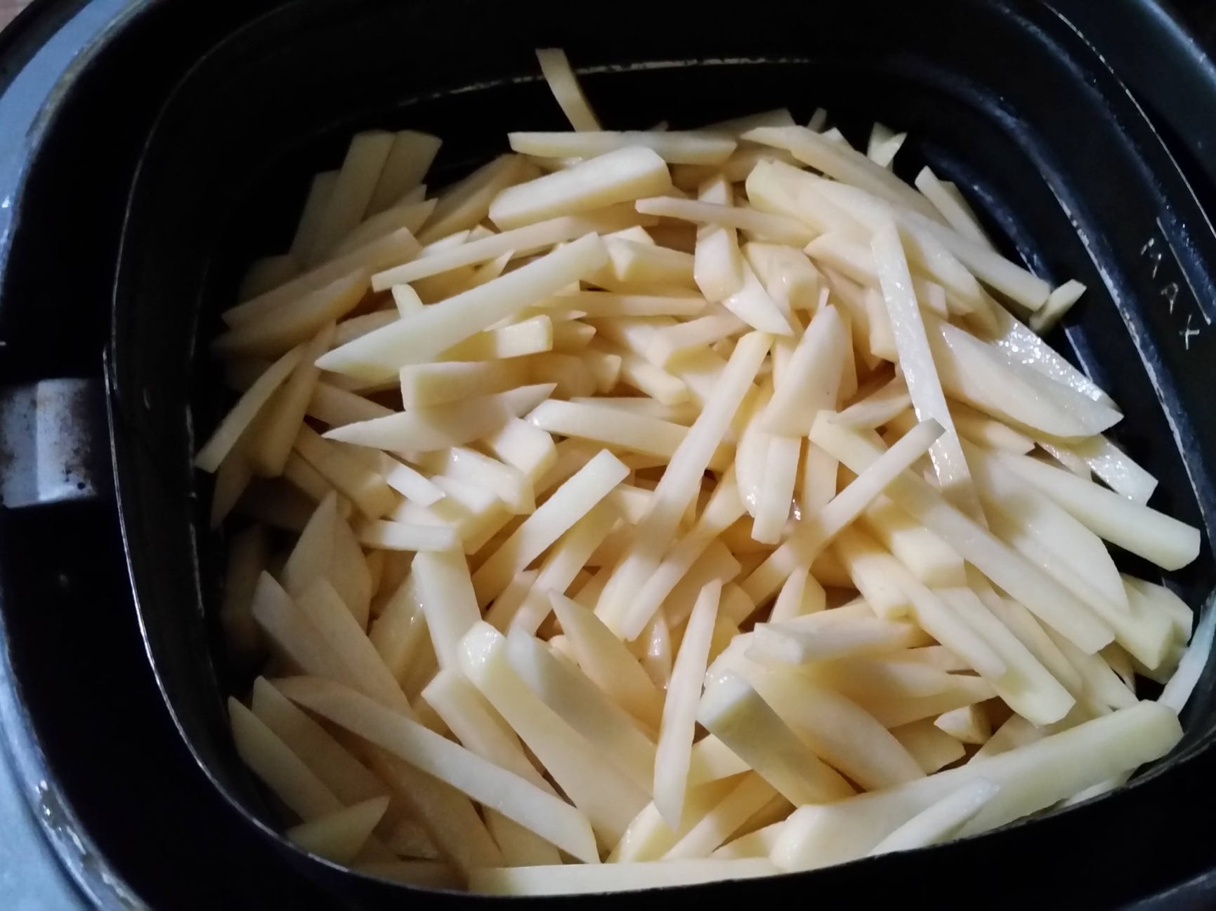 Uncooked french fries in an air fryer.