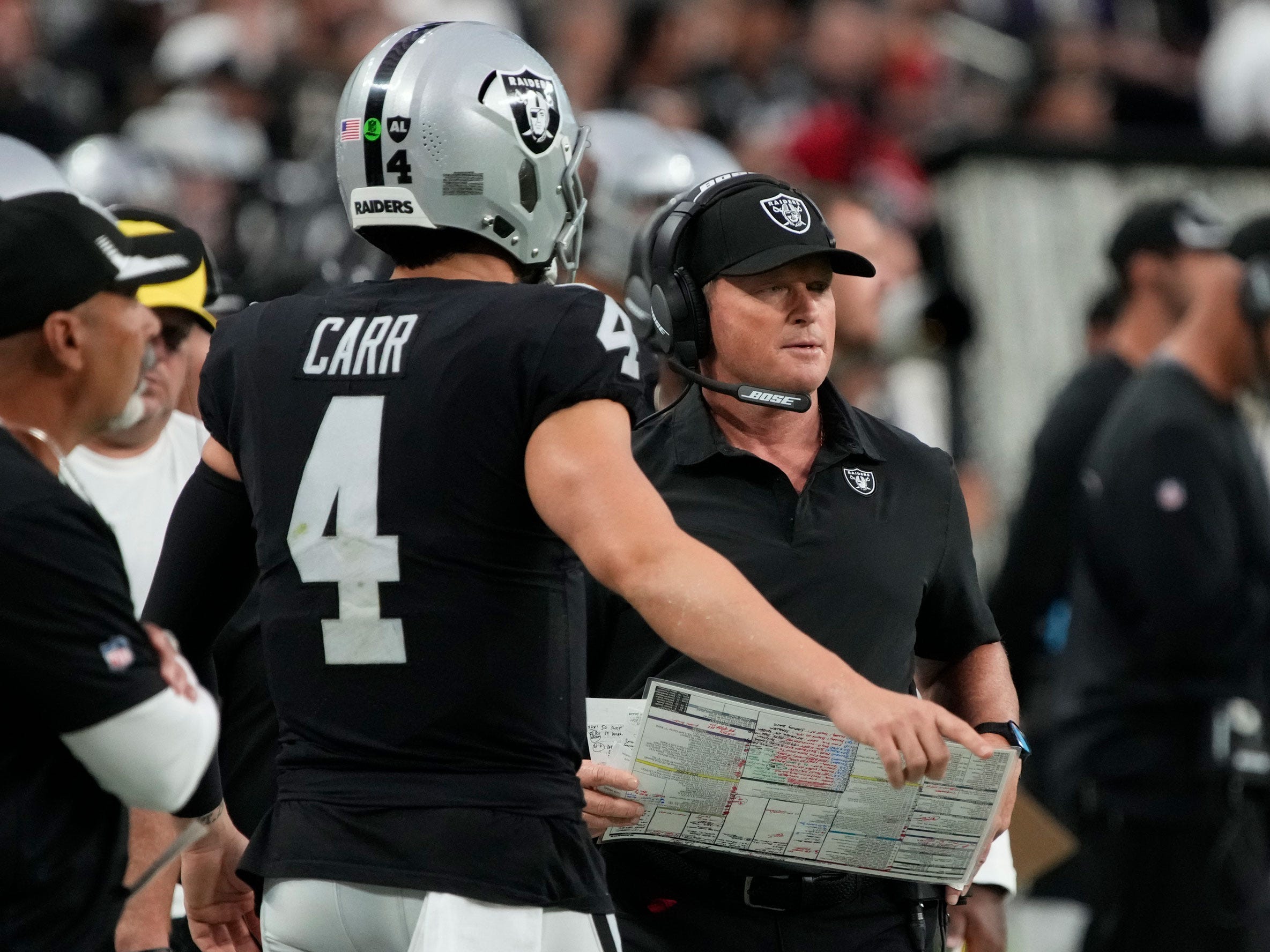 Jon Gruden and Derek Carr talk on the sideline.