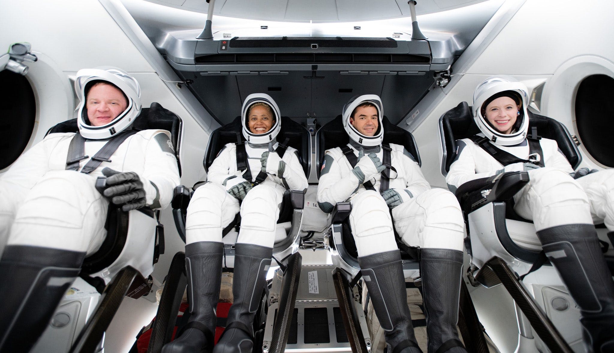 Inspiration4 passengers sit inside crew dragon spaceship seats wearing white spacesuits