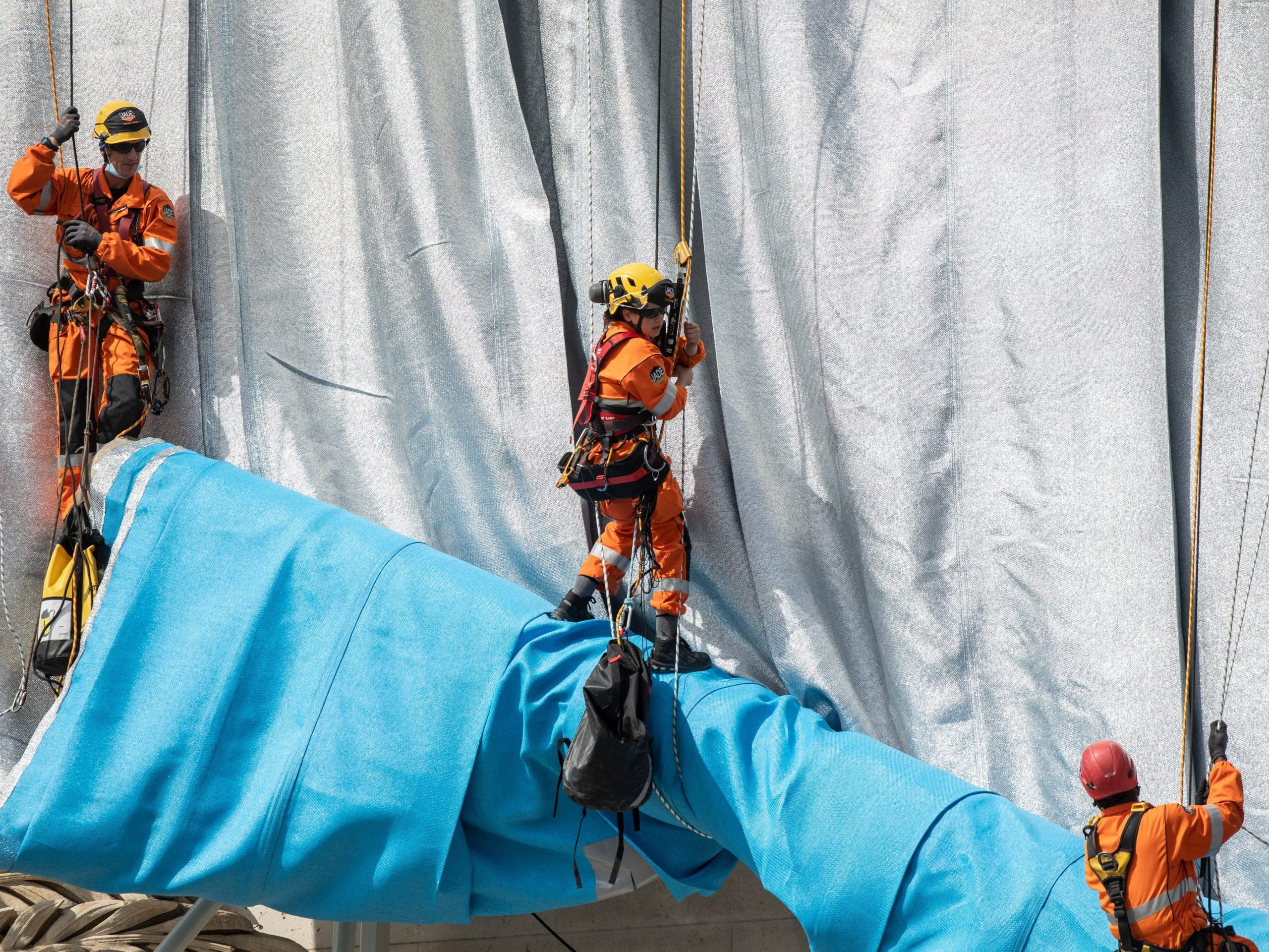 Workers applying silver-blue fabric to the Arc De Triomphe for the "Wrapped" installation on September 12, 2021, in Paris, France.