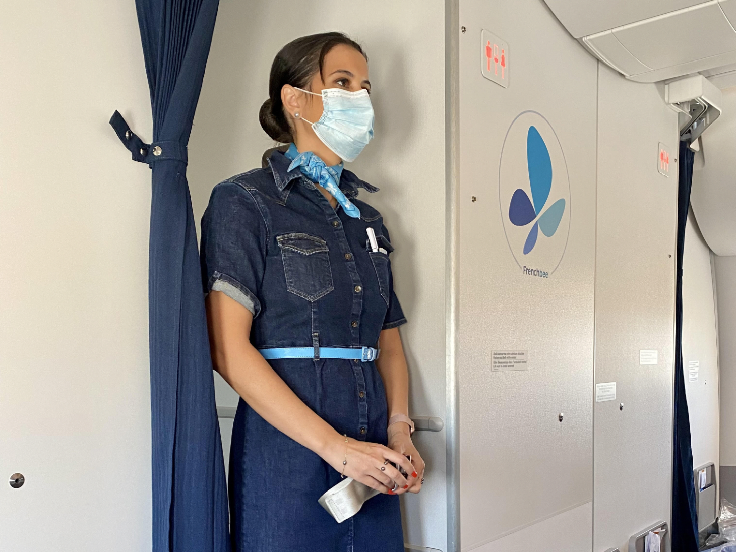 Frenchbee flight attendant wearing a surgical mask onboard