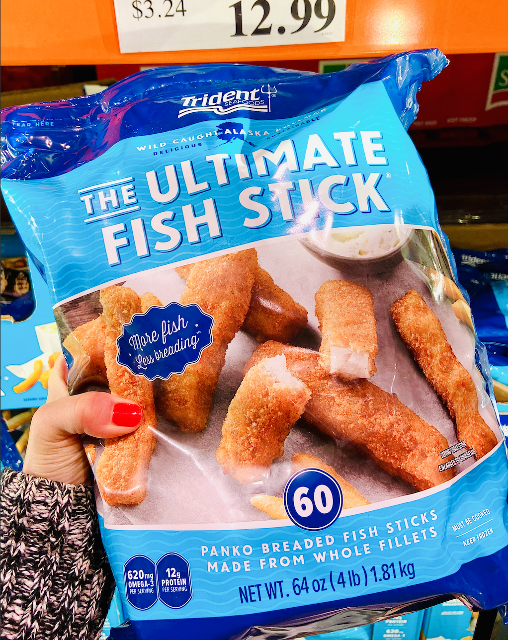 Hand holding a blue bag of fish sticks from costco