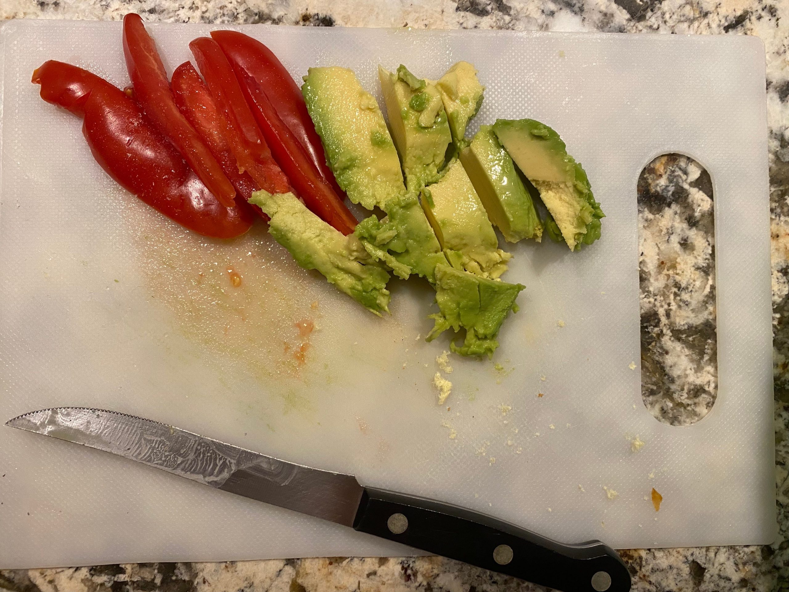 sliced tomato and avocado on a cutting board