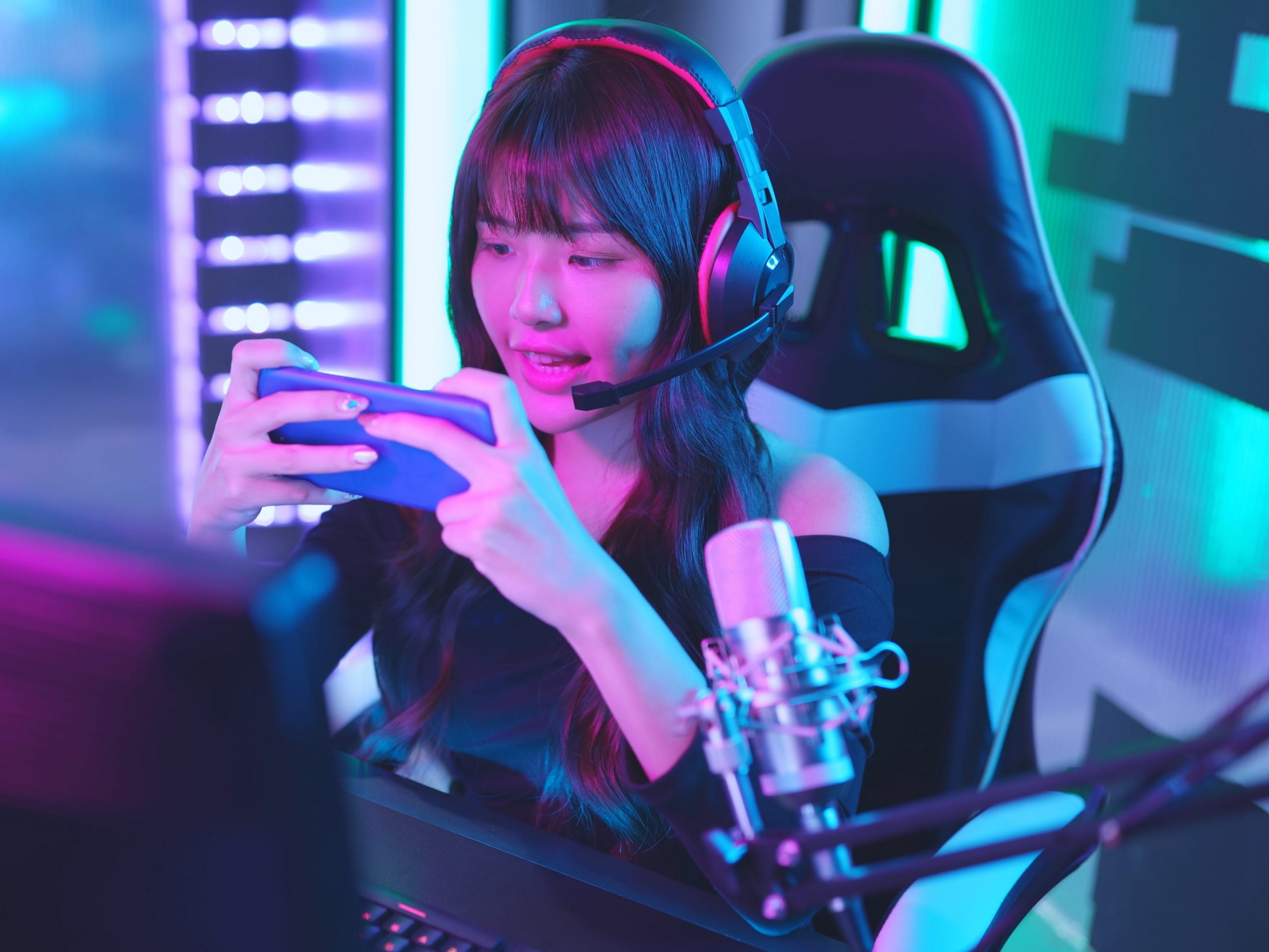Woman on phone with Bluetooth headphones during a gaming livestream.