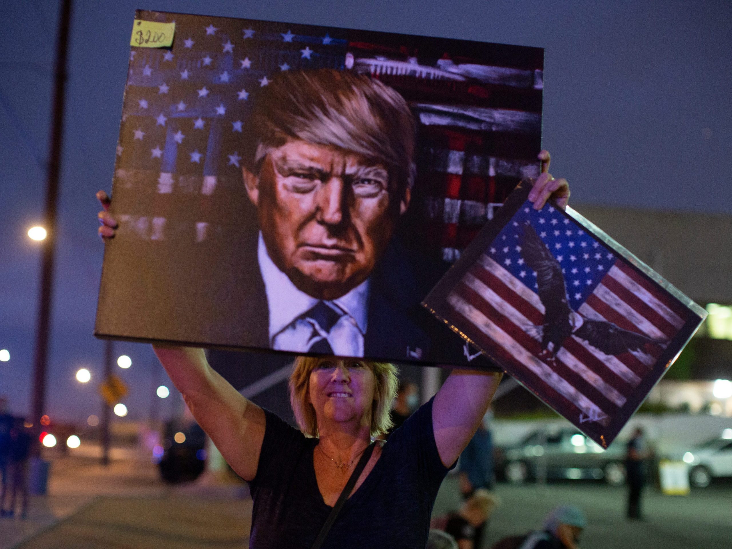 A supporter of former President Donald Trump holds up a painting of him outside of the Maricopa County Recorder's Office.