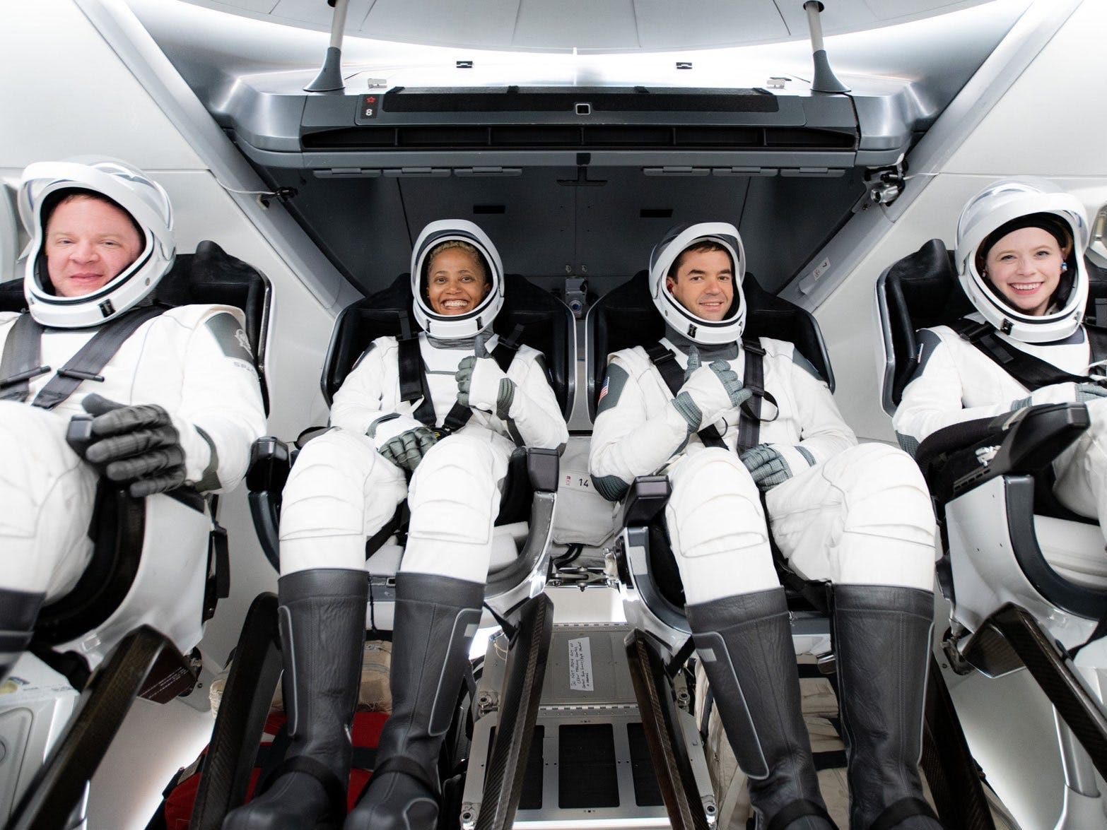 Inspiration4 passengers sit inside crew dragon spaceship seats wearing white spacesuits