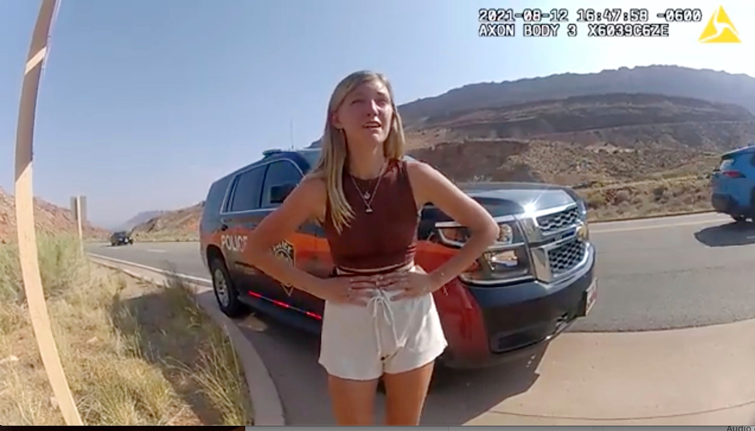 gabby petito with her hands on her hips in front of an SUV in the desert